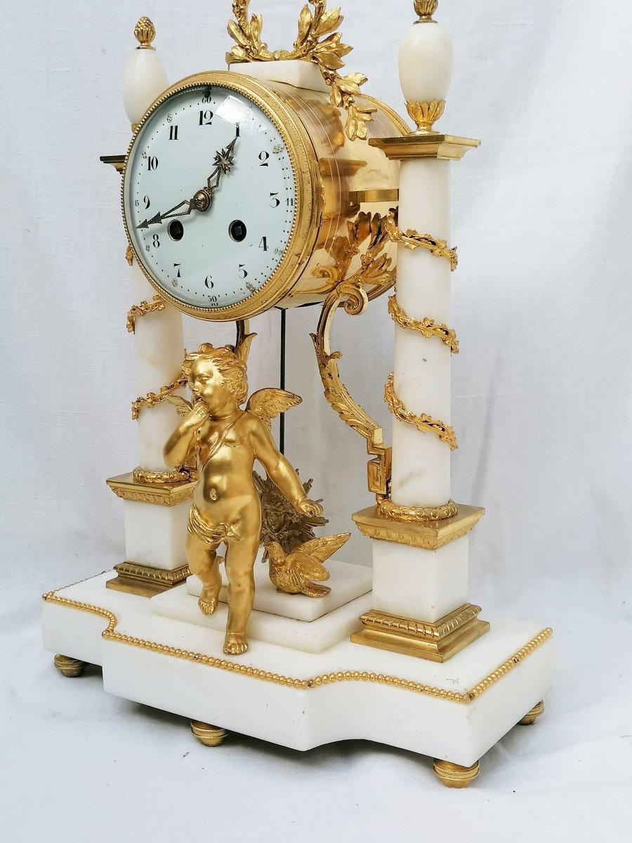 Table clock in white Carrara marble and gilt bronze ornaments in Louis XVIth style gilded with a putto on the terrace and leafy patterns surrounding the columns.
The mechanism signed Marty won a Gold medal at the 1900 World Fair.
The movement
