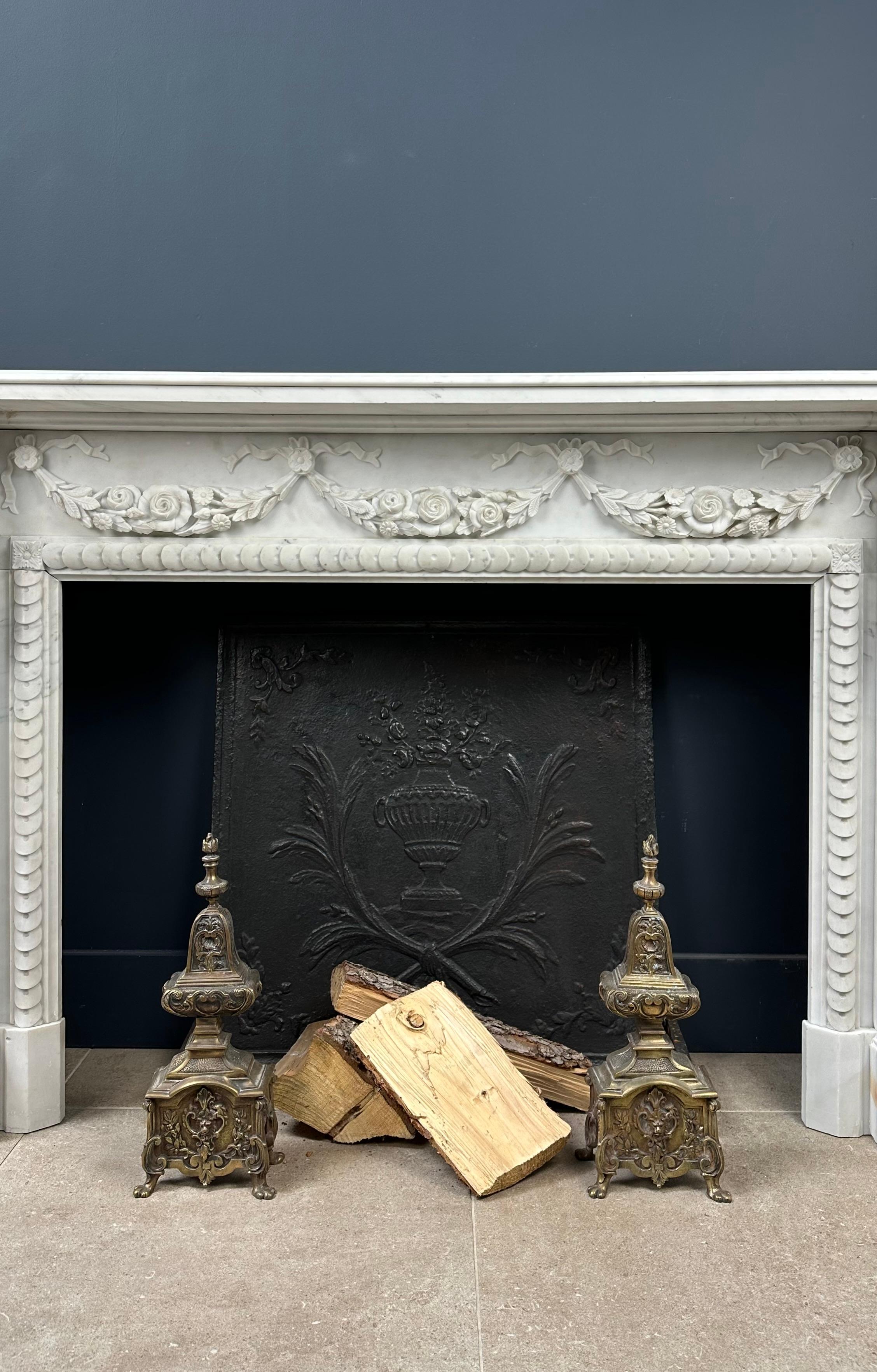 Introducing our exquisite Antique White Marble Front Fireplace, adorned with captivating details in Carrara Marble. Prepare to be enchanted by this extraordinary discovery! This unique fireplace, embellished with beautifully carved garlands,