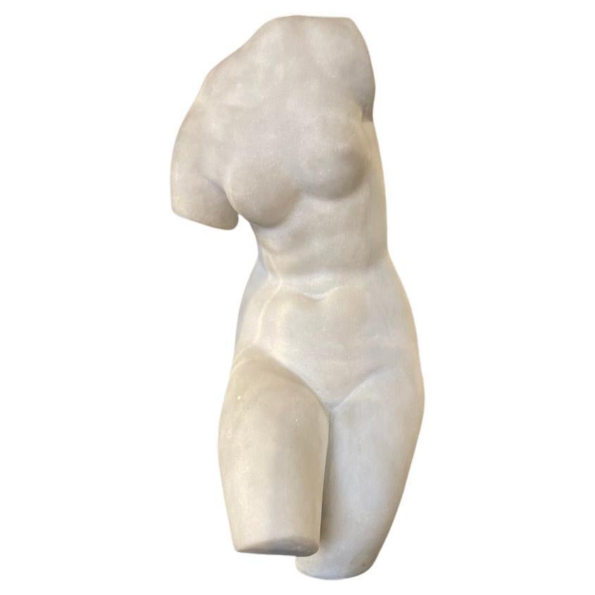 Anmutige Skulptur aus weißem Carrara-Marmor aus den 1950er Jahren, die den Torso einer weiblichen Figur darstellt.
Das Stück steht auf einem schwarzen Marmorsockel, der seine Eleganz und den Materialkontrast unterstreicht.
Trotz ihrer kompakten