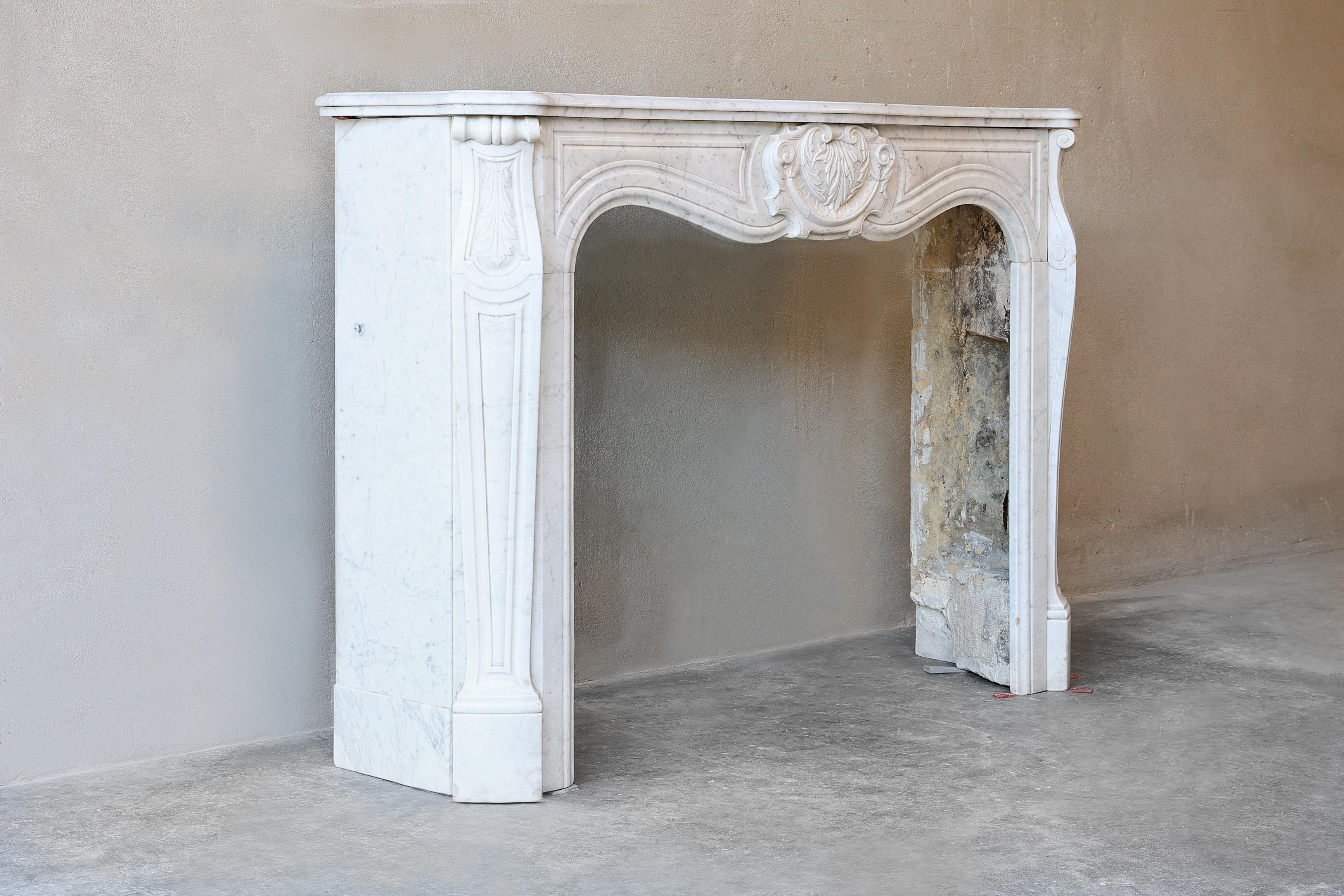 Beautiful antique fireplace mantelpiece made of Carrara marble from the 19th century in the style of Louis XV. Equipped with a beautiful ornament in the middle and also beautiful ornaments on the legs. A very beautiful fireplace that can be used in