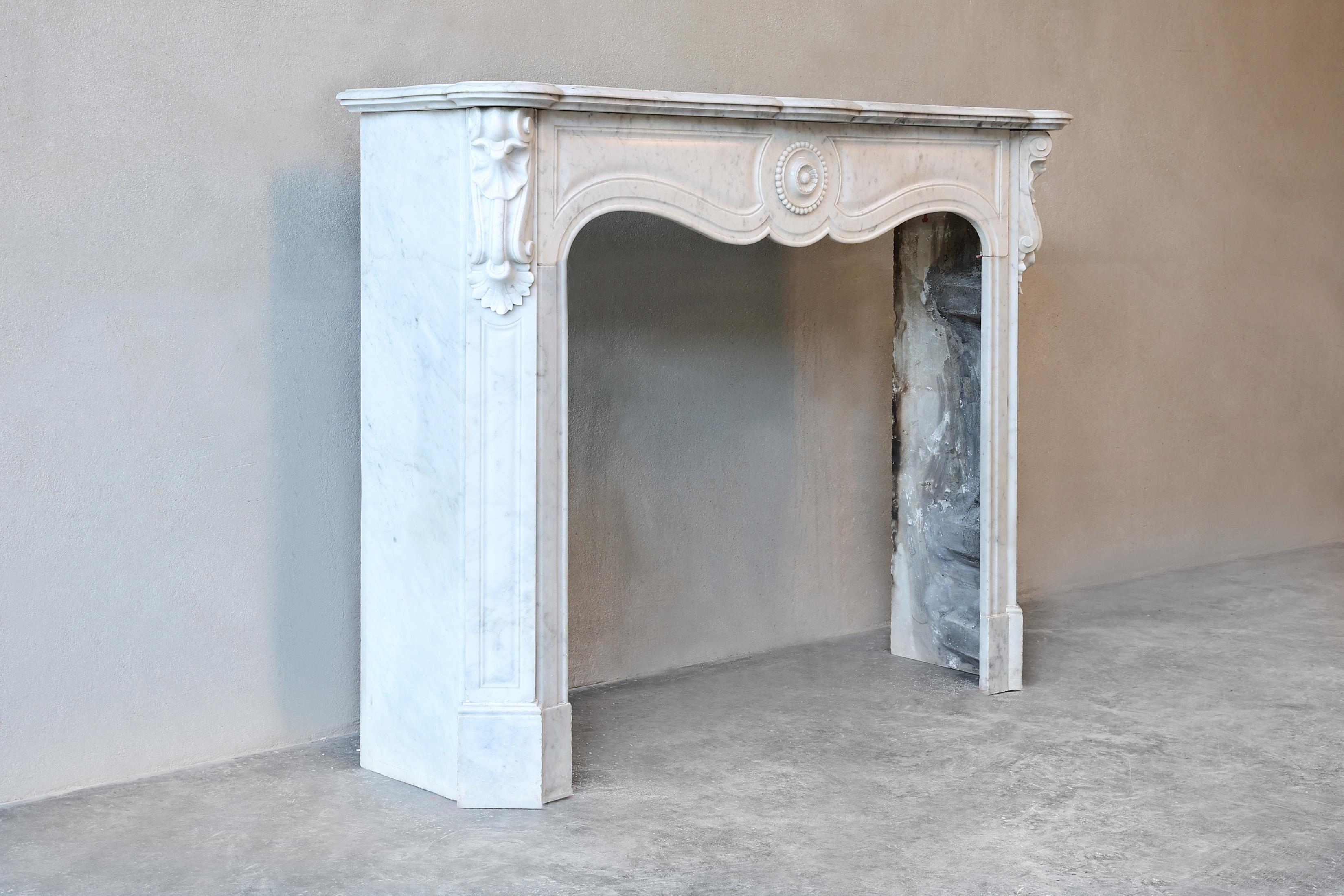Beautiful friendly antique fireplace of Carrara marble from the 19th century. This fireplace is in Pompadour style and has beautiful ornaments in the front part and on the legs! The format is compact and suitable for many interiors.