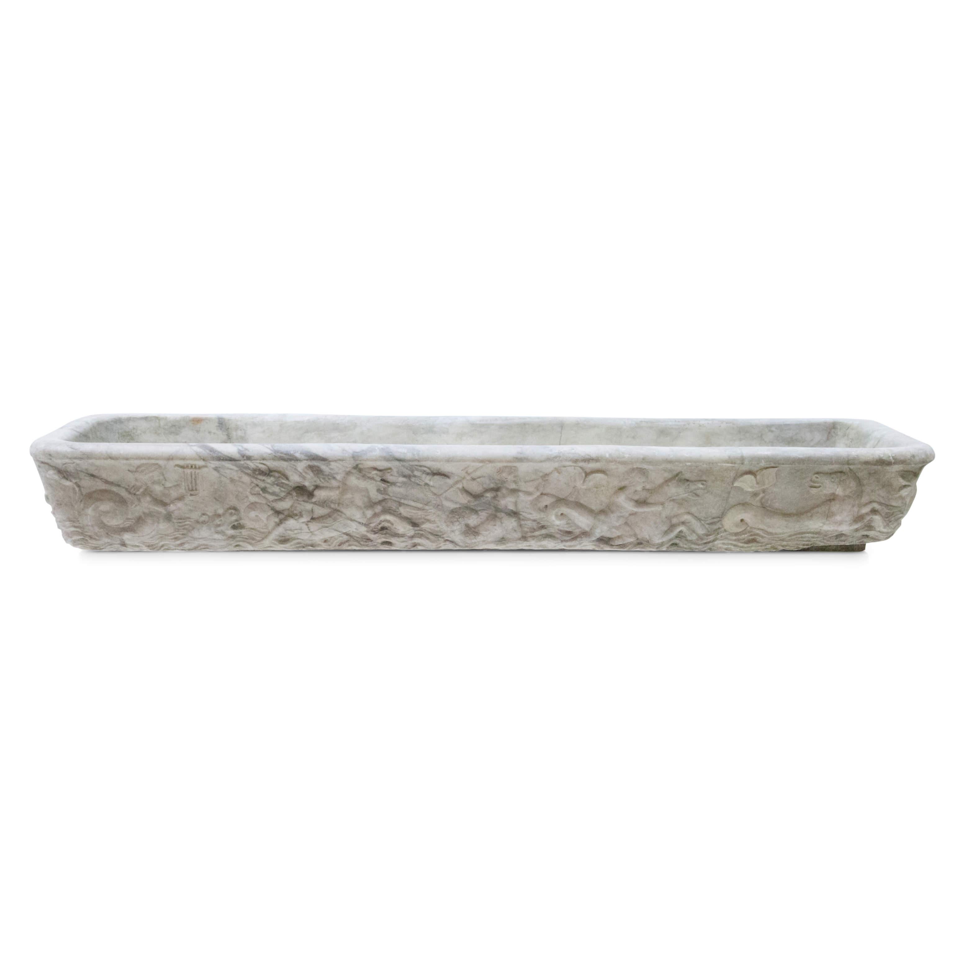 Long rectangular fountain basin in Carrara marble with relief depiction of mythological scenes on the wall.
 