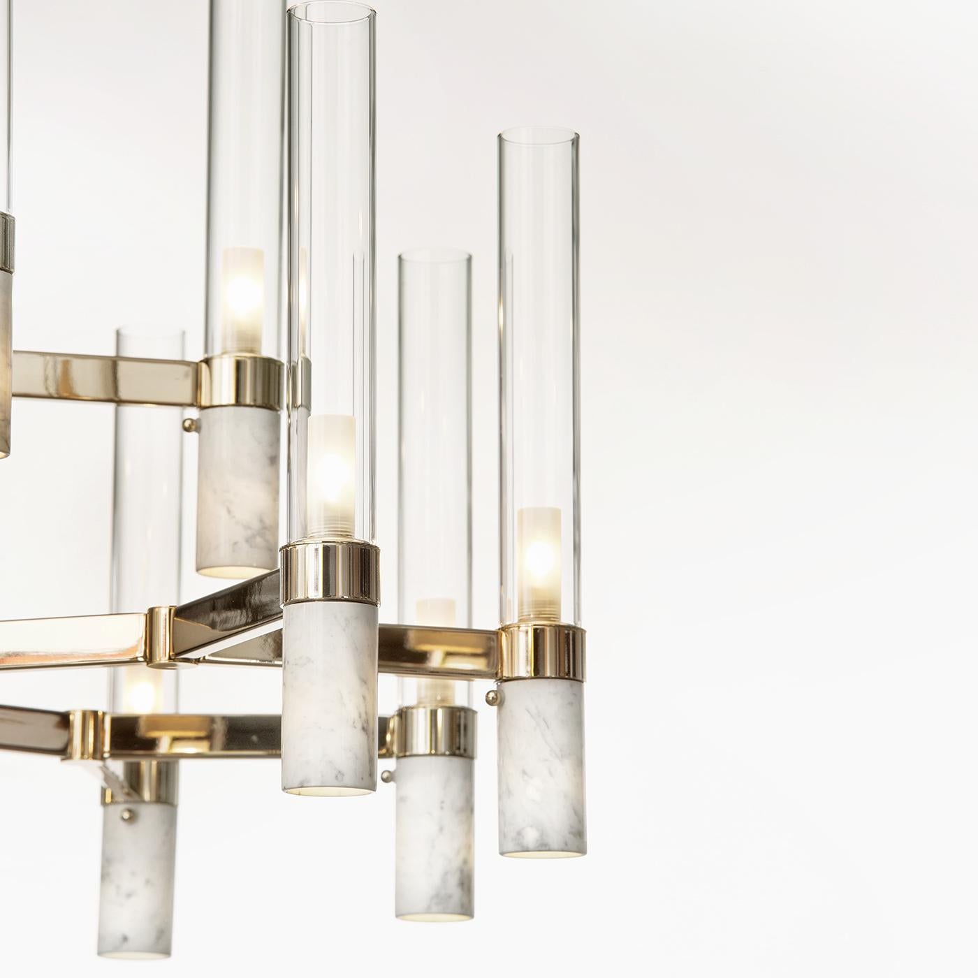 Di ispirazione classica, questo maestoso lampadario vanta un design di tendenza che si adatta agli interni moderni e contemporanei. La struttura in metallo ha una morbida finitura dorata e mostra 18 bracci orizzontali che partono da un'asta
