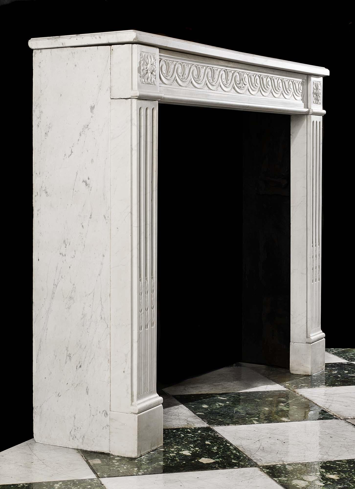 A simply carved Carrara Marble Louis XVI antique fireplace surround with Vitruvian scrolled decoration on the frieze flanked by floral paterae on the endblocks above stop fluted jambs.
French, early 19th century.
  