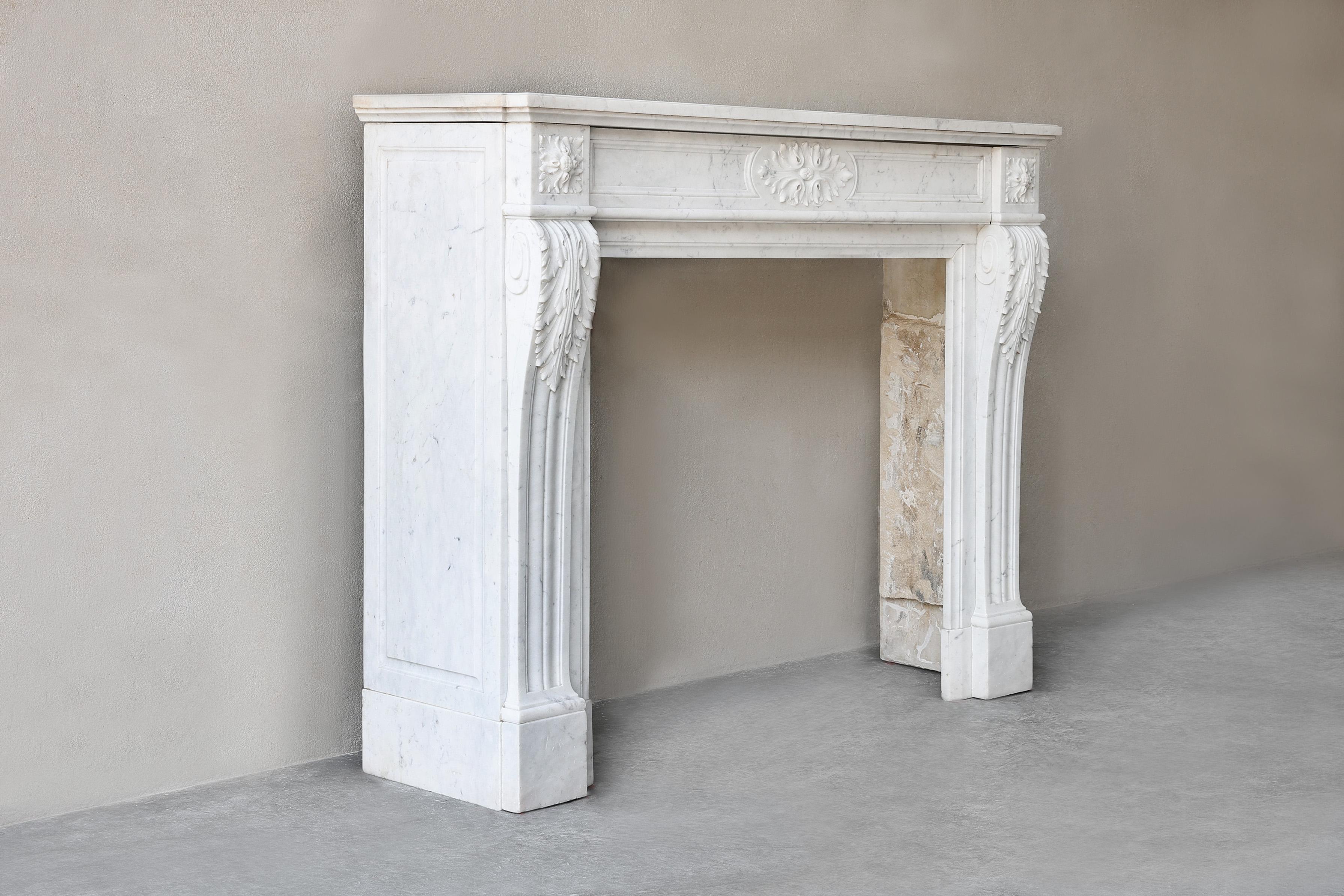 Beautiful antique marble fireplace made of white Carara marble from Italy. This 19th century fireplace is in the style of Louis XVI. The consoles are provided with fluting, acanthus leaves and rosettes in the corners. A very graceful and elegant