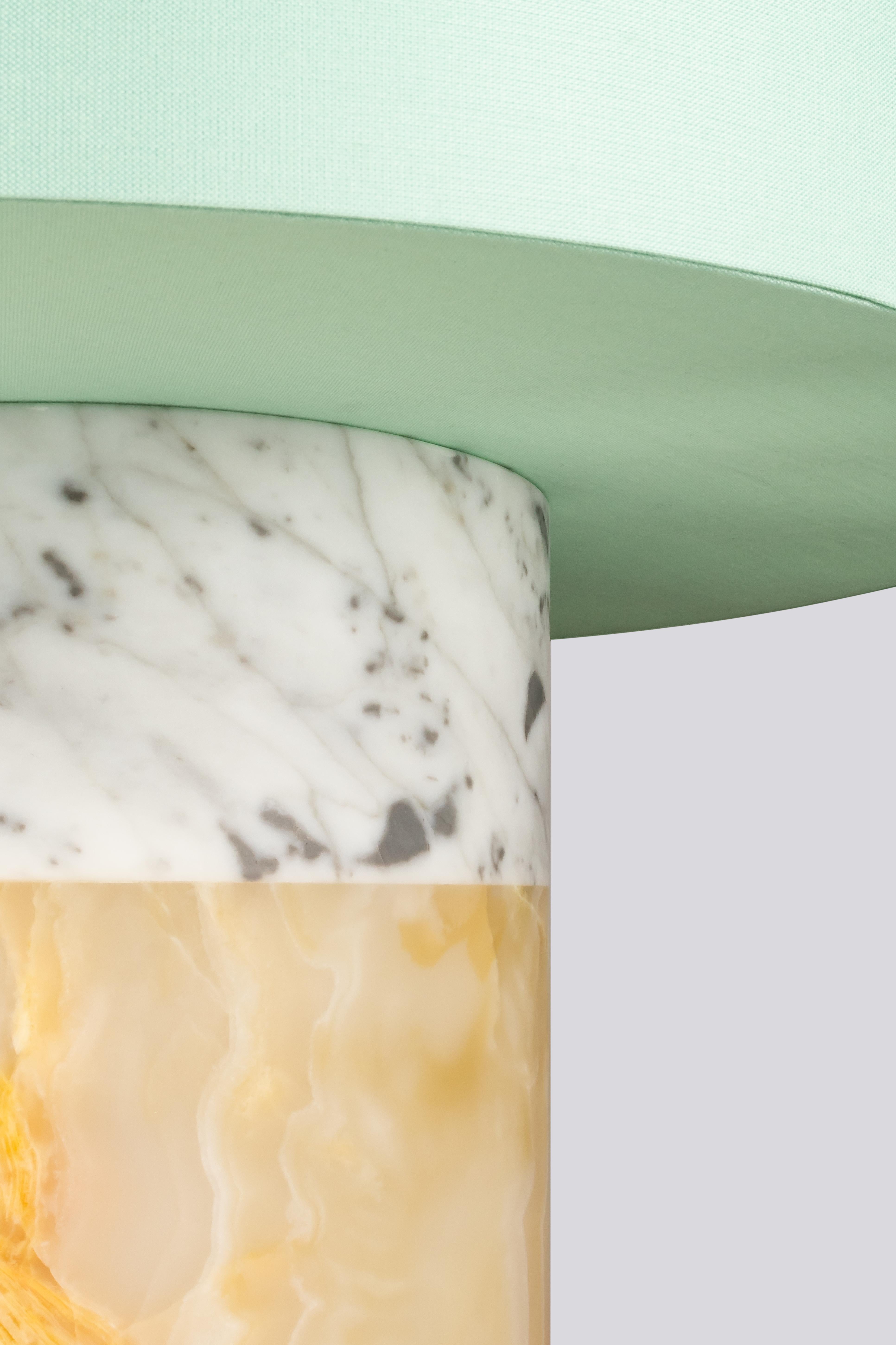 Entdecken Sie unsere exquisite Tischleuchte aus Marmor und Onyx, ein zeitloses und modernes Stück, das Eleganz und Handwerkskunst vereint. Der fachmännisch in klassischer Säulenform gefertigte Sockel der Leuchte präsentiert zwei luxuriöse