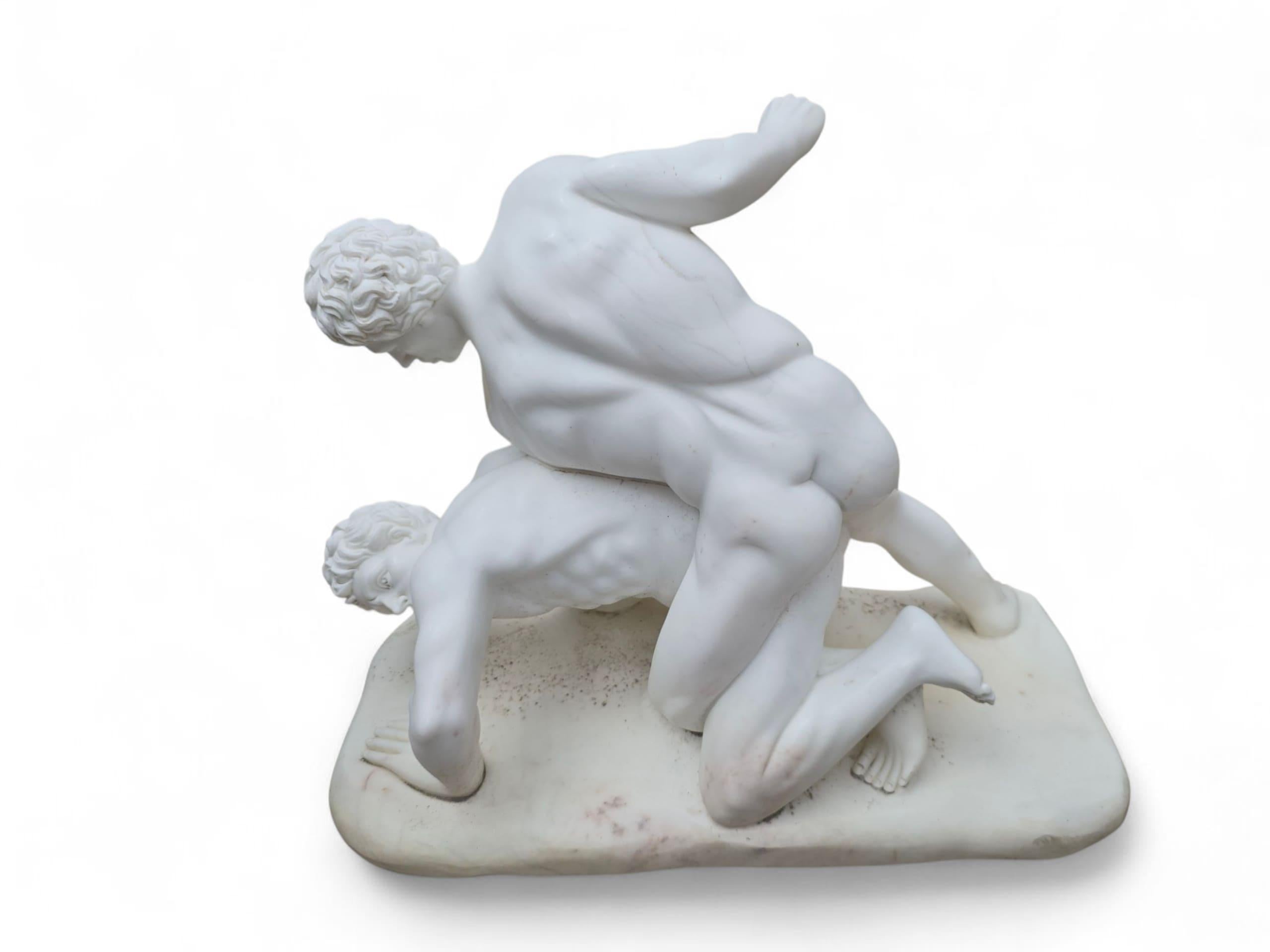 Dynamic marble sculpture carved from fine Italian Carrara marble, depicting two classical wrestlers engaged in combat. Inspired by ancient Greco-Roman athletic forms, the piece captures tension, movement, and anatomical precision with remarkable