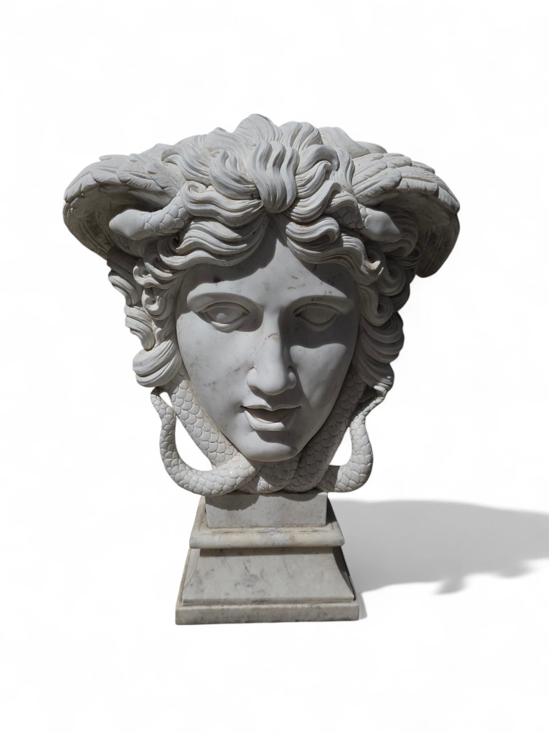 Elegante Marmorskulptur, die den Kopf der Medusa darstellt und meisterhaft aus feinem weißen Carrara-Marmor gehauen wurde. In Anlehnung an die griechische Mythologie fängt das Werk die markanten und ausdrucksstarken Züge der Gorgone ein -