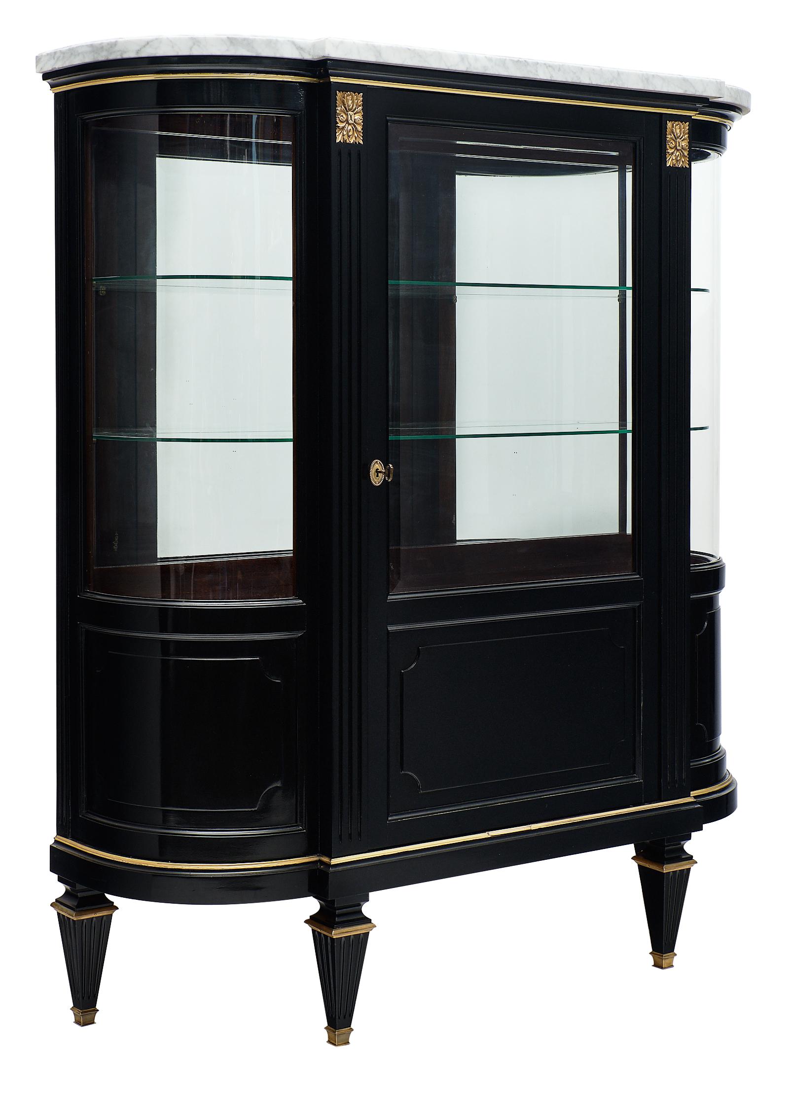 Louis XVI style antique bookcase with Carrara marble top. This piece is made of solid mahogany with all original brass trim, hardware, and mirrored interior. The glass shelves give the interior additional sophistication. This argentier (display