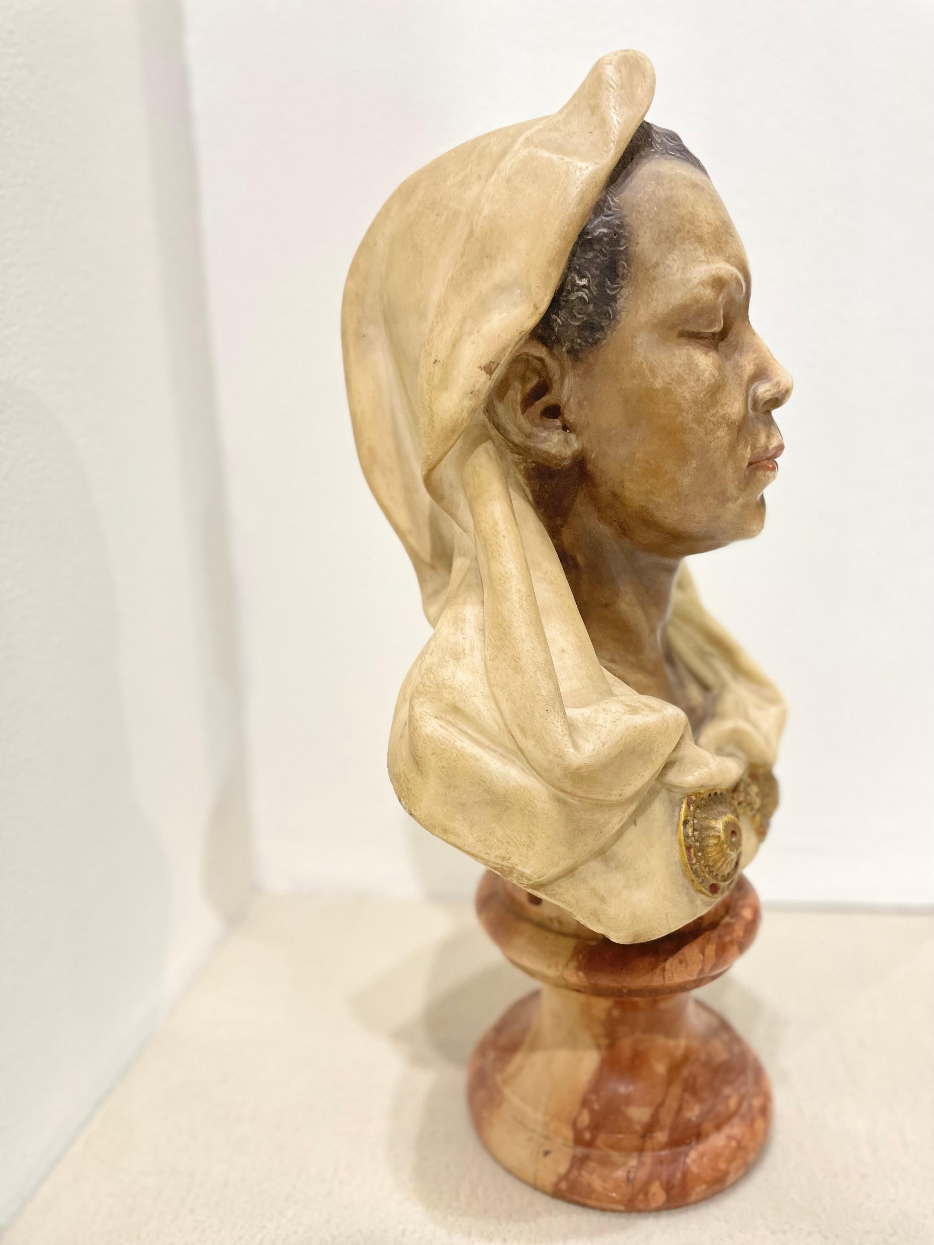 Bust sculpted in Carrara marble. Nubian polychrome is extremely well-executed giving a realistic effect. A white veil is attached by a golden fibula. Red marble base. Signed on the back Marchetti.