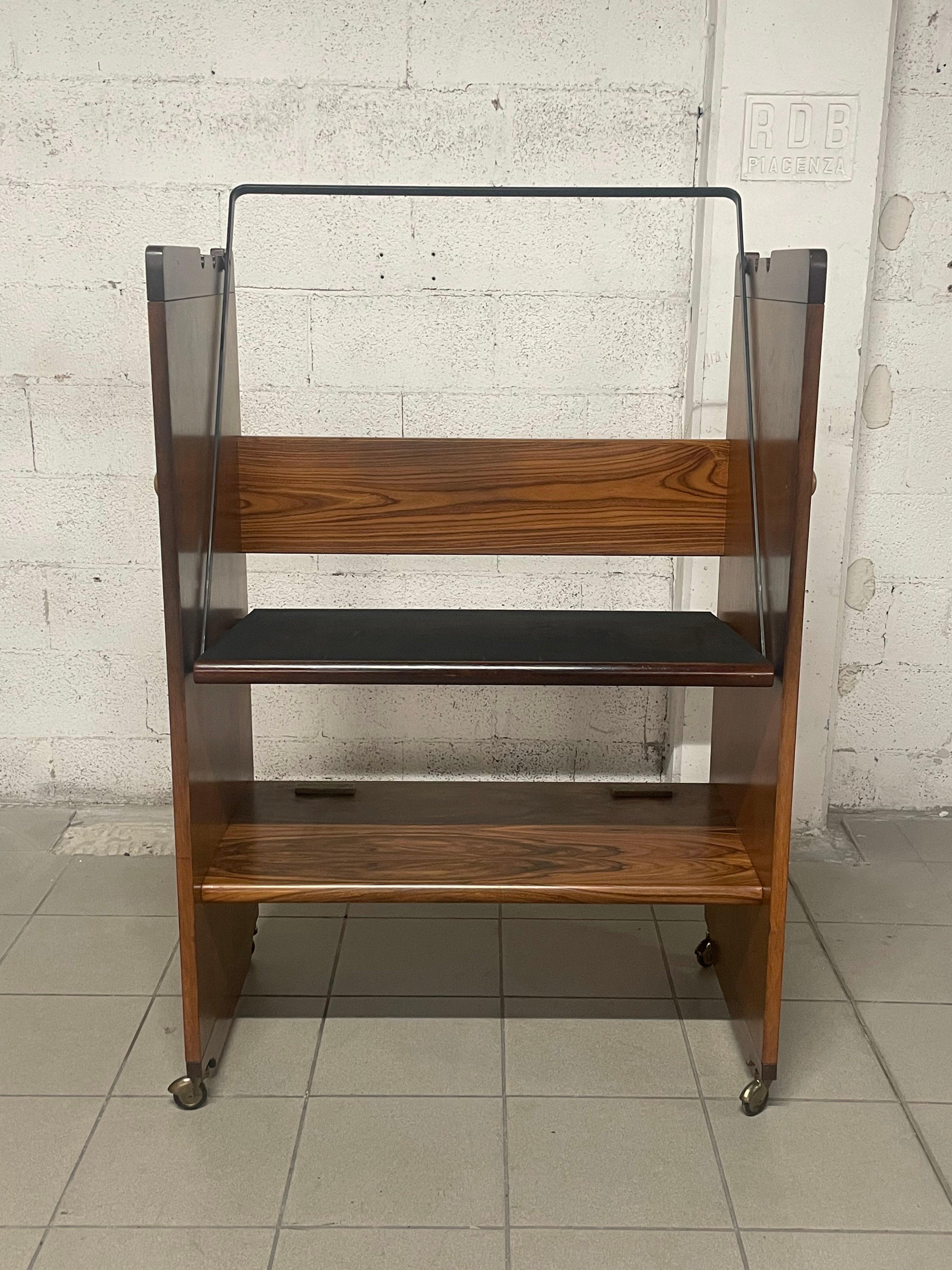 TV-Ständer aus den 1970er Jahren, hergestellt von Bernini (Markenname sichtbar).

Holzrahmen, Walnussfurnier und Gummi für den TV-Träger, 4 Räder für leichte Bewegung.
Der TV-Träger kann in 3 verschiedene Positionen gebracht werden, um seine Neigung