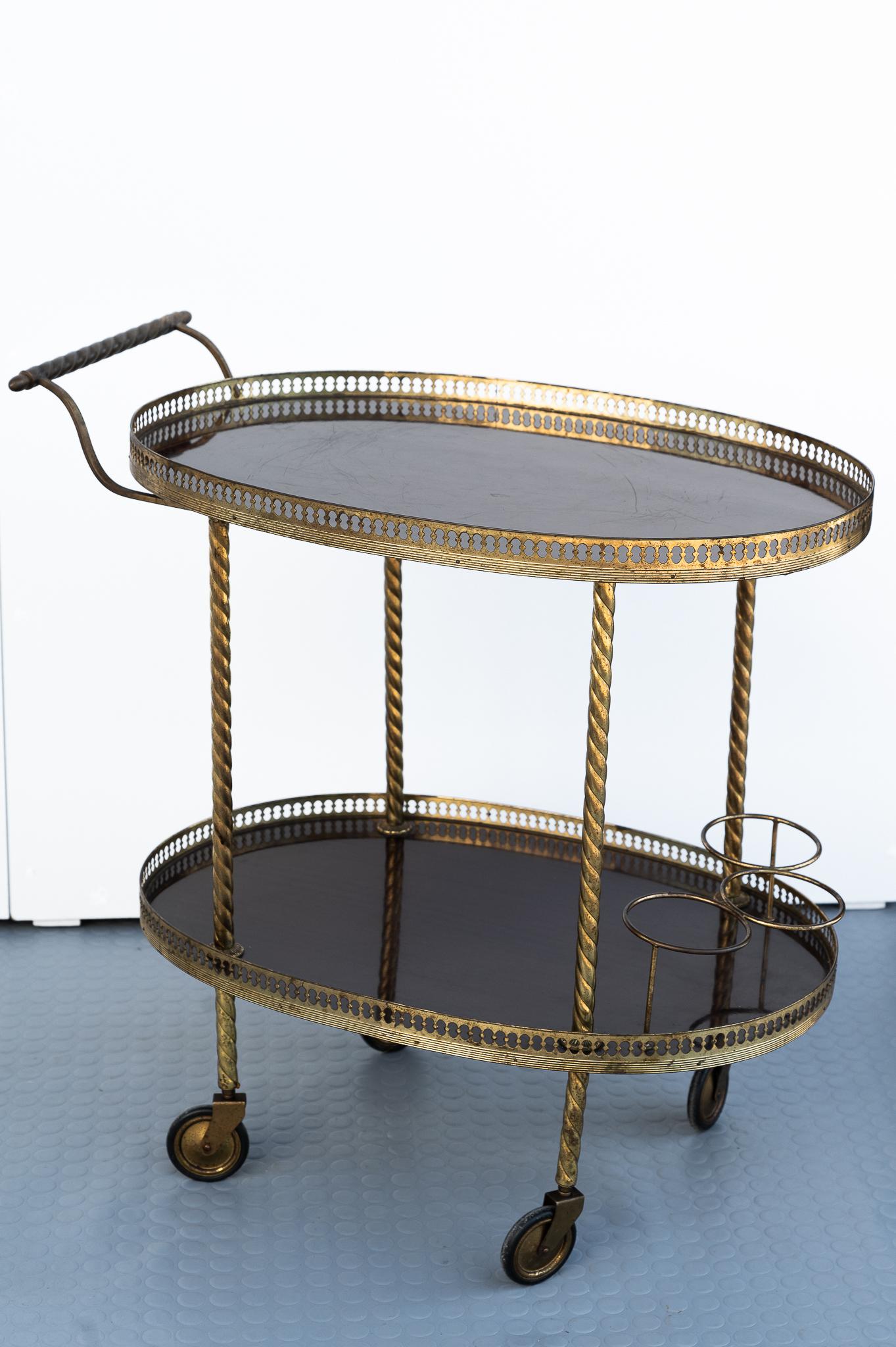 Bar cart, Made in Italy, 1960s. 
Trolley made in Italy in the 1960s for Beverage and Cocktail bars. Positioned on top of four wheels, the legs of the frame are filigree brass around oval trays with bottle holders. It is in very good condition, has