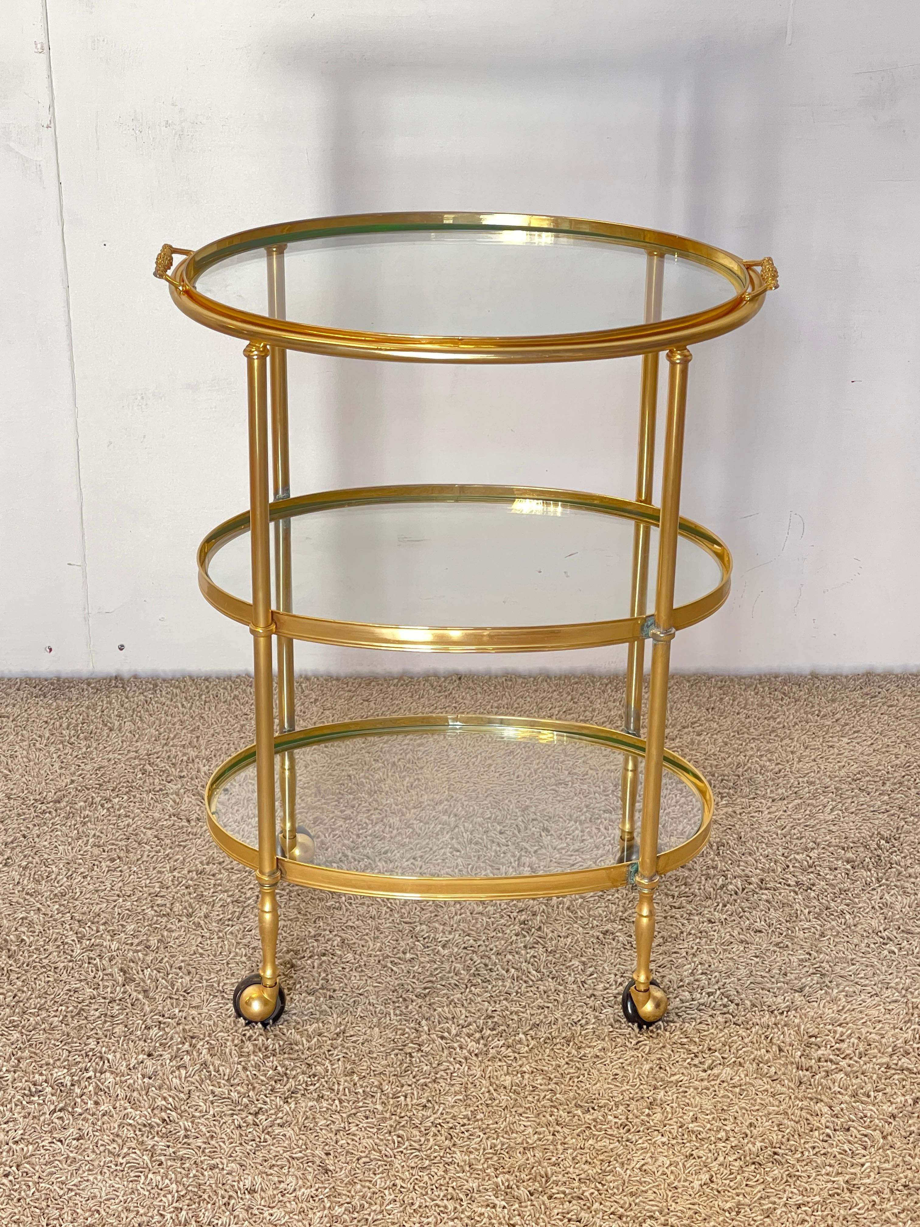 Elegante carrello bar vintage in ottone dorato con tre ripiani in vetro. La structure ovale et les lignes étroites évoquent le style raffiné de Hollywood Regency, tandis que les ruines originales permettent un traitement simple et fluide.

Un objet