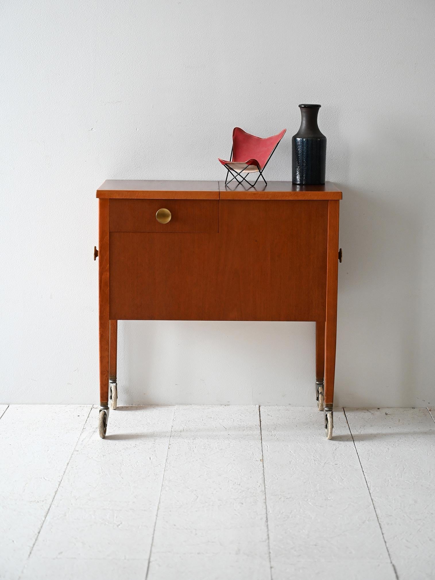 Mobile su ruote anni ’50/’60 in mogano, con contenitore apribile e cassetto laterale.

Mobile contenitore su ruote originali, realizzato in mogano e risalente agli anni ’50/’60. Il piano si apre a libro rivelando un vano interno profondo. Sul lato