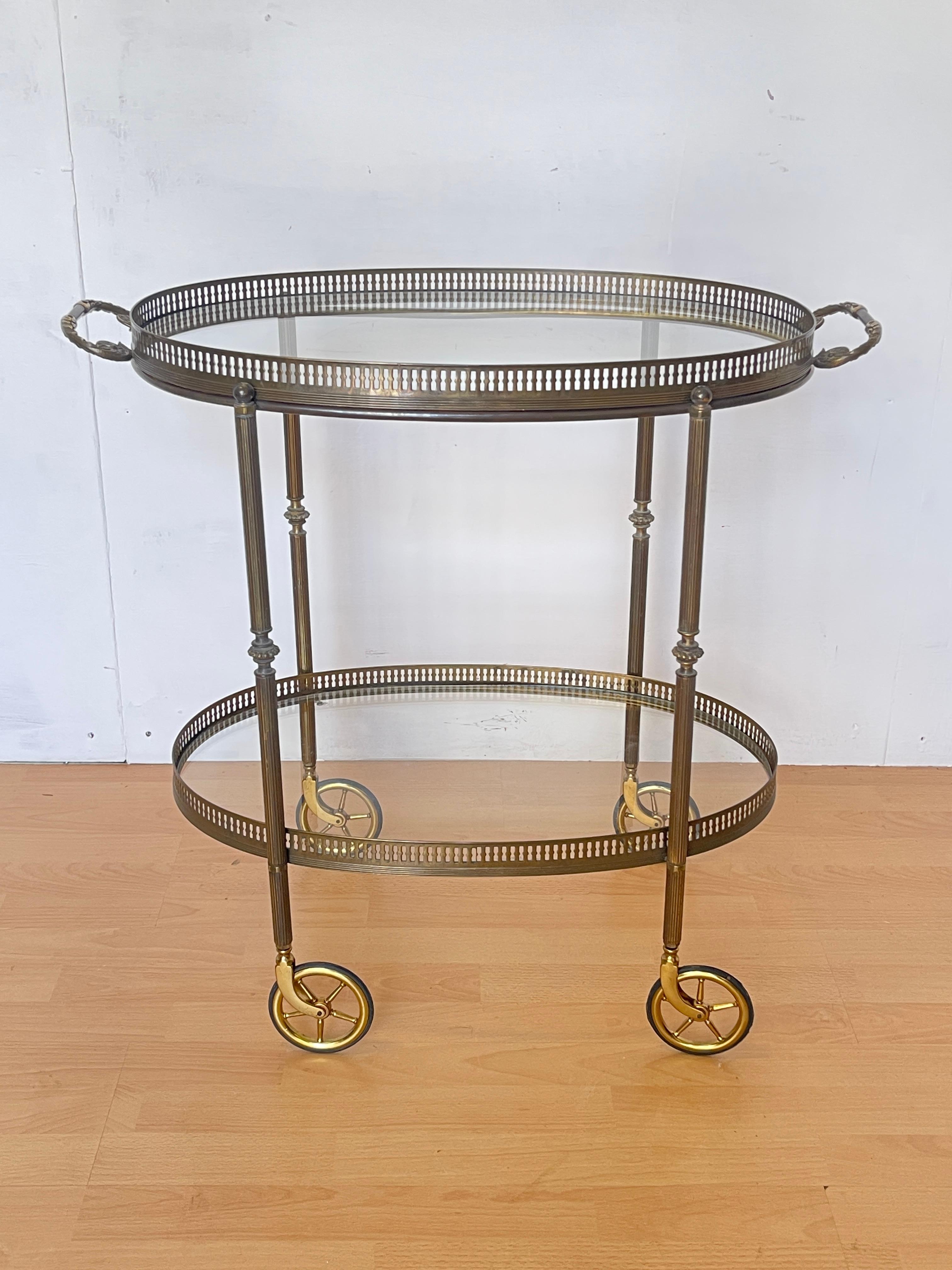 Ce chariot de service vintage raffiné, en laiton bruni avec des étagères en verre transparent, incarne le style néoclassique typique des années 1950. Ses lignes épurées et ses proportions harmonieuses en font une pièce polyvalente et décorative,