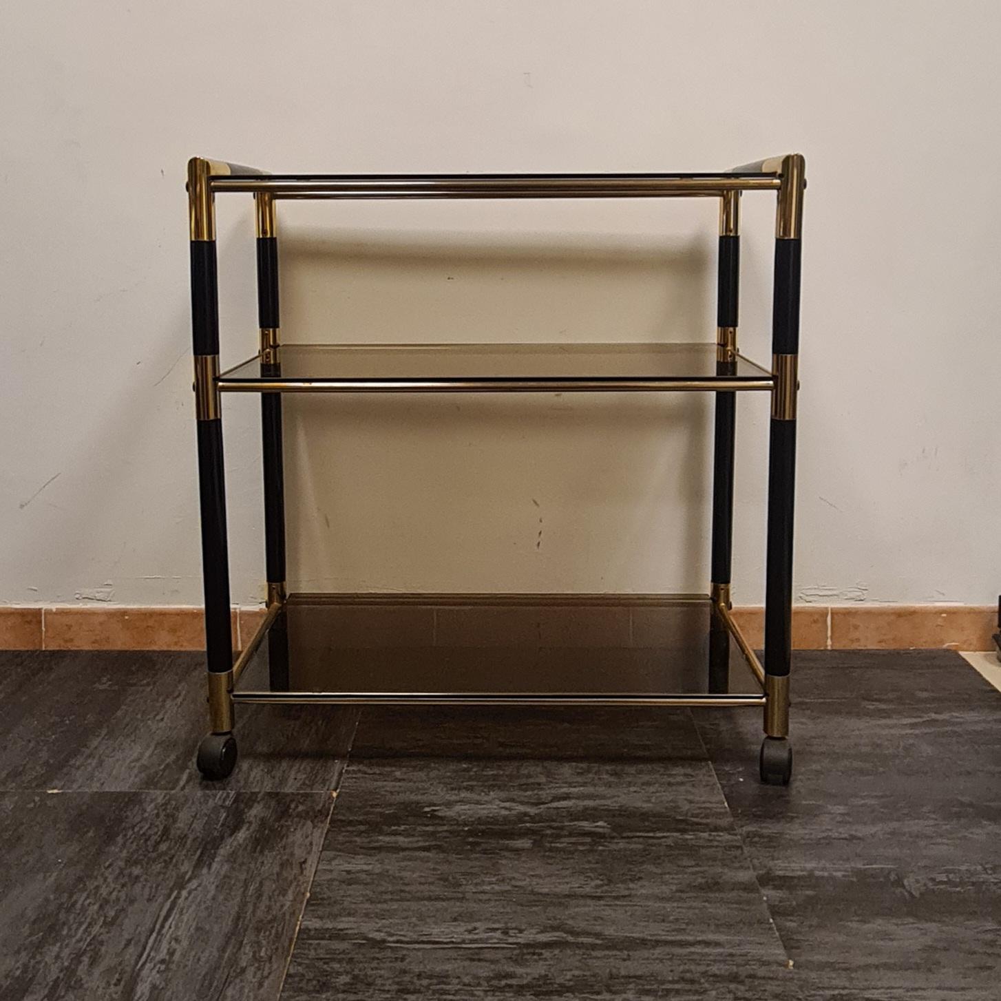 Elegant food cart by designer Tommaso Barbi.

The three-tiered trolley is made of a cylindrical lacquered wood frame with brass details and trim.

The three shelves are made of smoked glass.

Tommaso Barbi is a highly regarded Italian designer, his