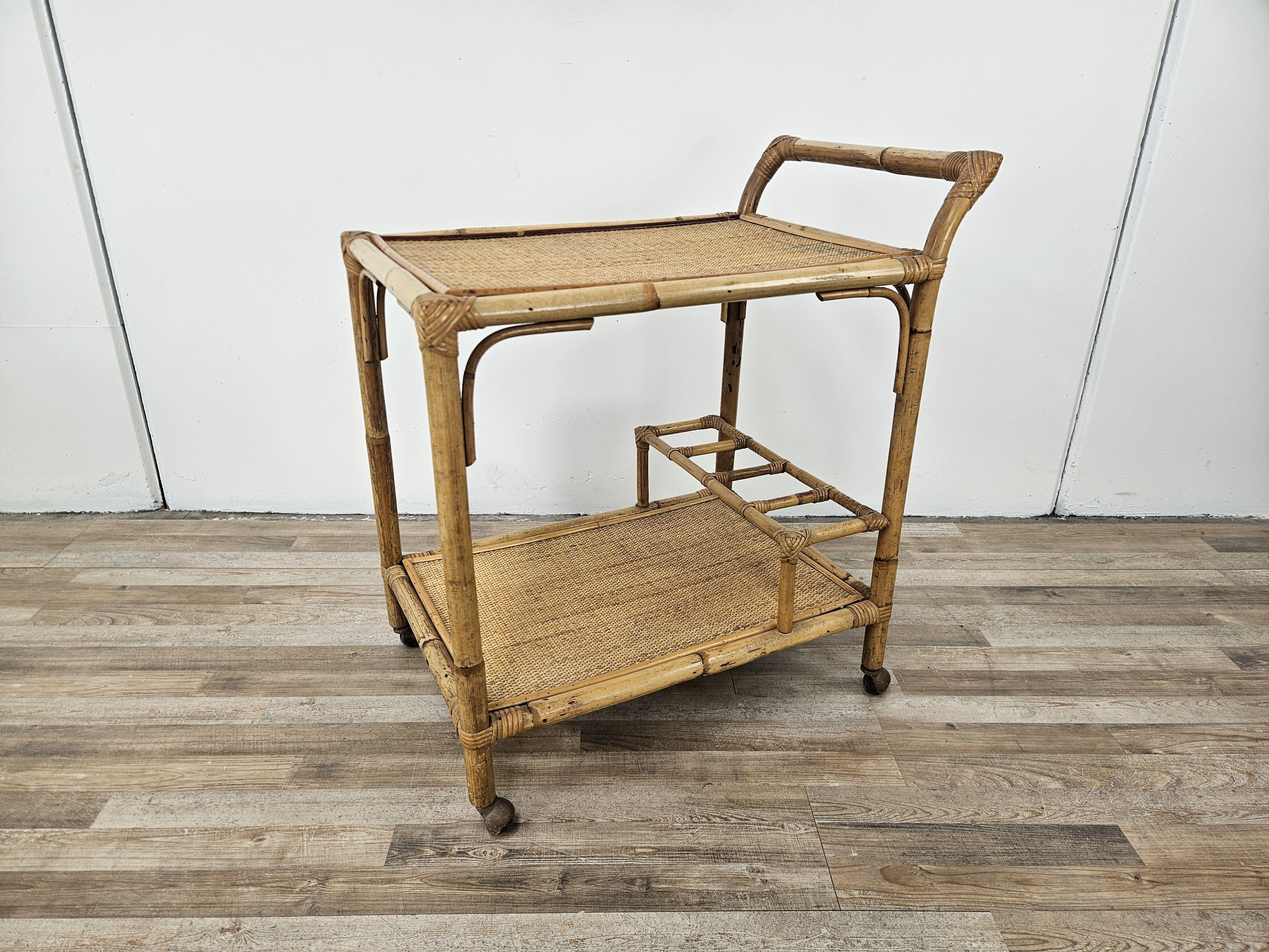 Carrello da cucina o soggiorno in vimini anni '70 con doppio ripiano e scomparto porta bottiglie.

Le ruote sono originali e funzionanti.

Normali segni d'usura dovuti da età e utilizzo.