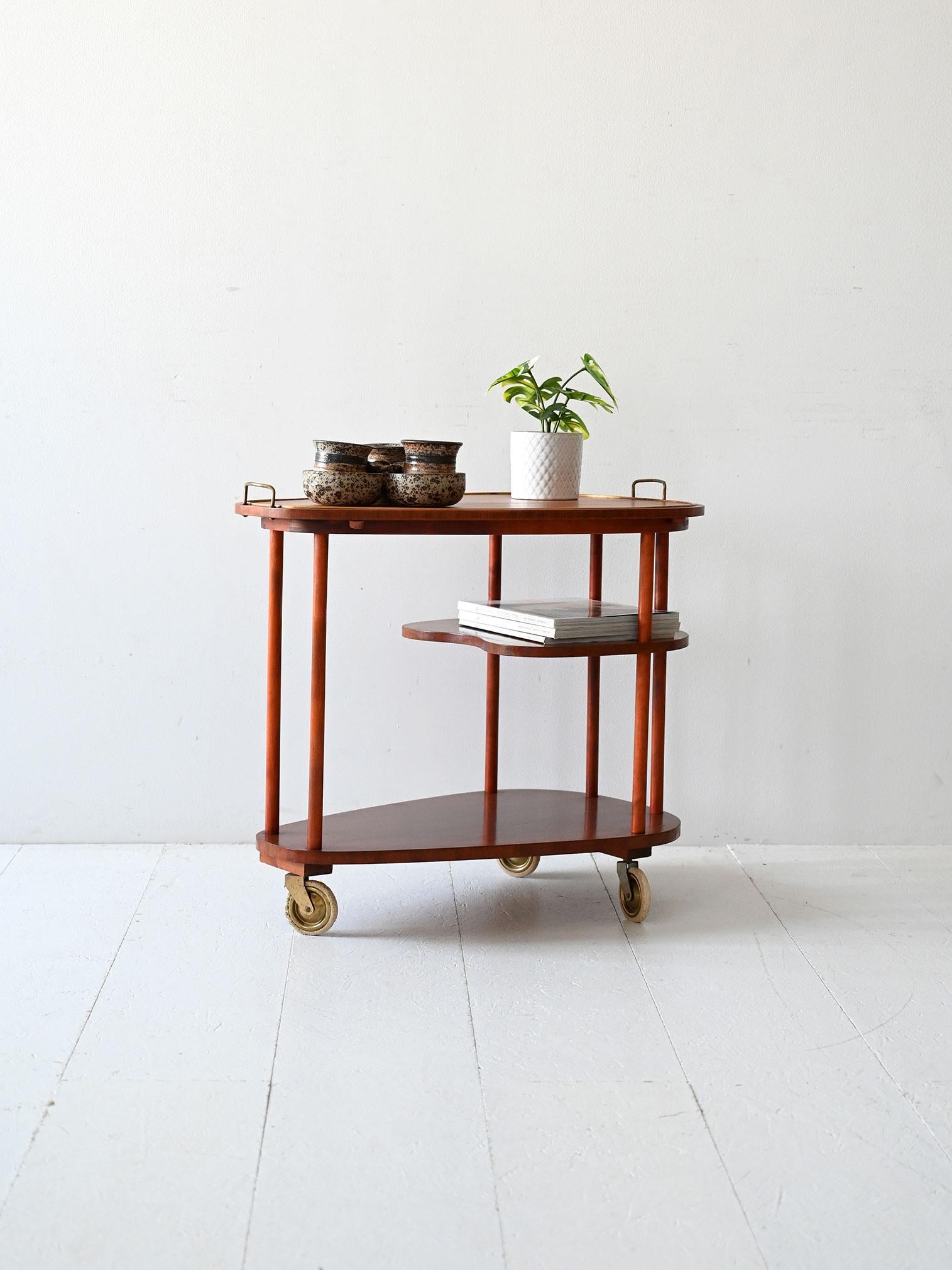 Élégant chariot scandinave en acajou des années 1940 avec trois étagères de forme organique et des roulettes en laiton d'origine.

Chariot scandinave vintage des années 1940 en acajou avec trois étagères de forme organique. La structure légère,