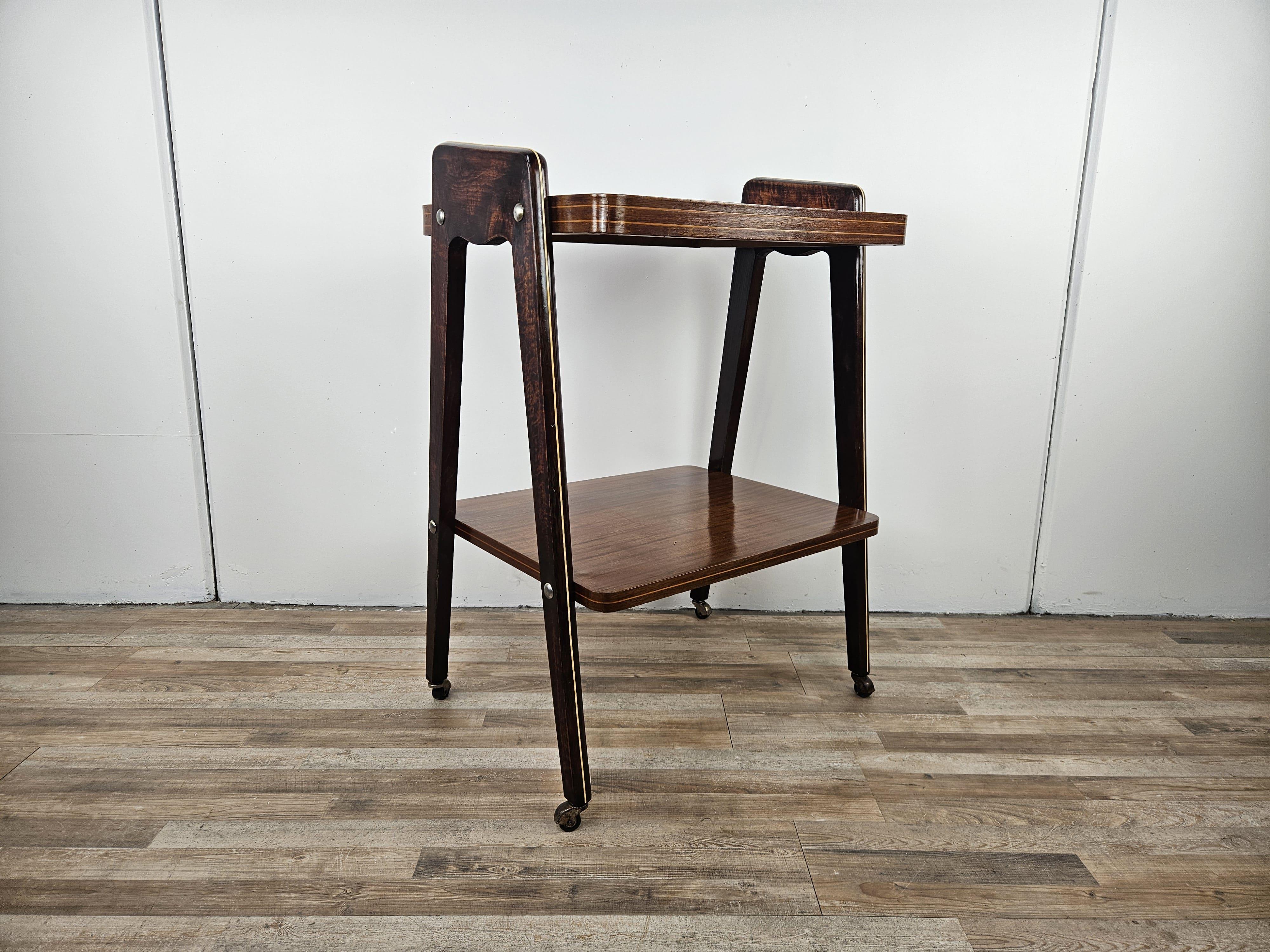Carrello vintage dei primi anni '50 di epoca Art Decò, con due ripiani e base su quattro rotelle.

Il carrello può essere utilizzato anche come tavolino di servizio o come tavolino in salotto e all'ingresso.

Lucidato ad olio, presenta normali segni