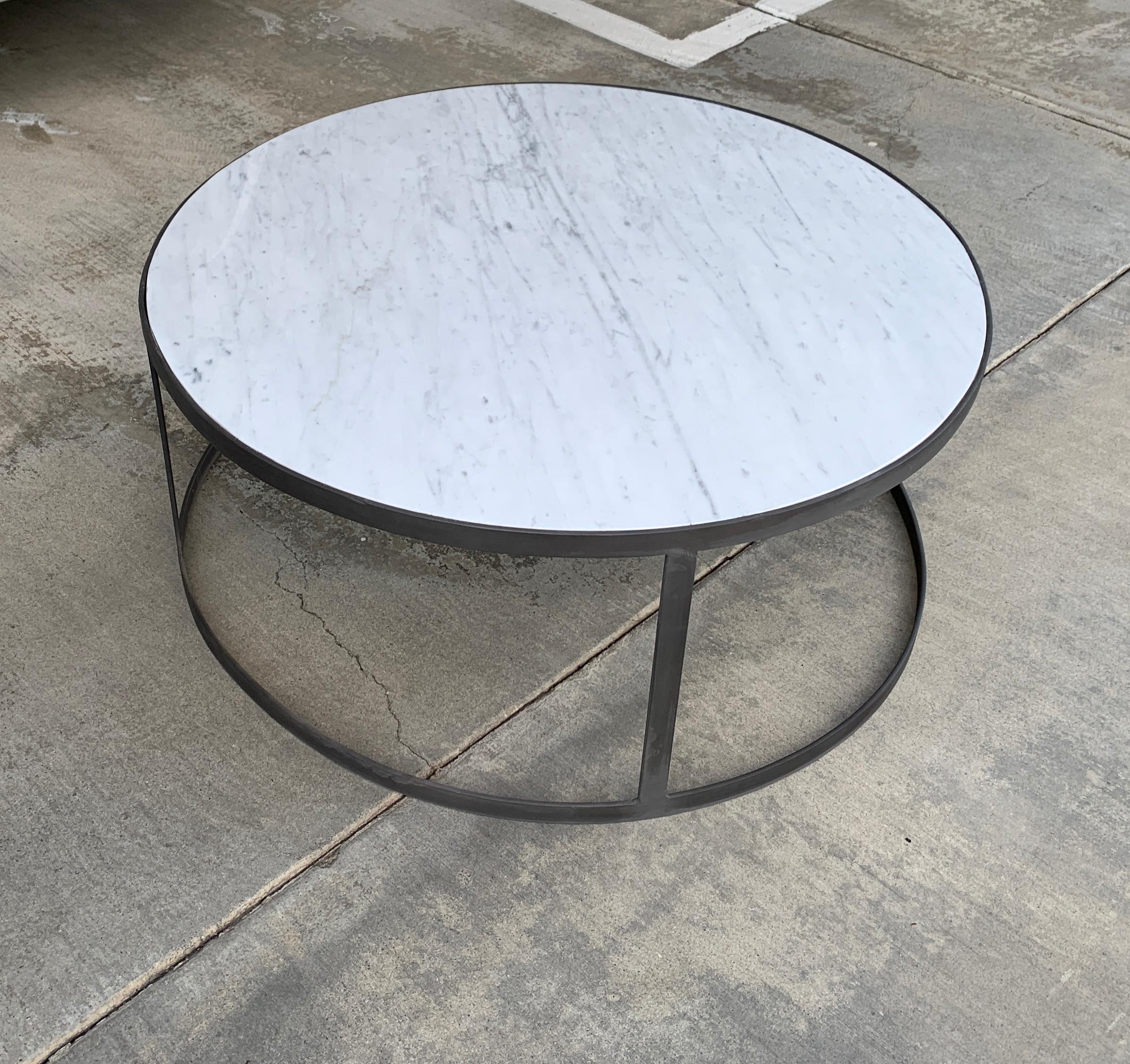 Une table basse en marbre de Carrare avec une base ronde en finition fer. Le dessus est neuf et la base est vintage. Nous avons dû remplacer l'ancien plateau qui s'était cassé. La base a été recouverte d'une finition en fer, veuillez voir les photos