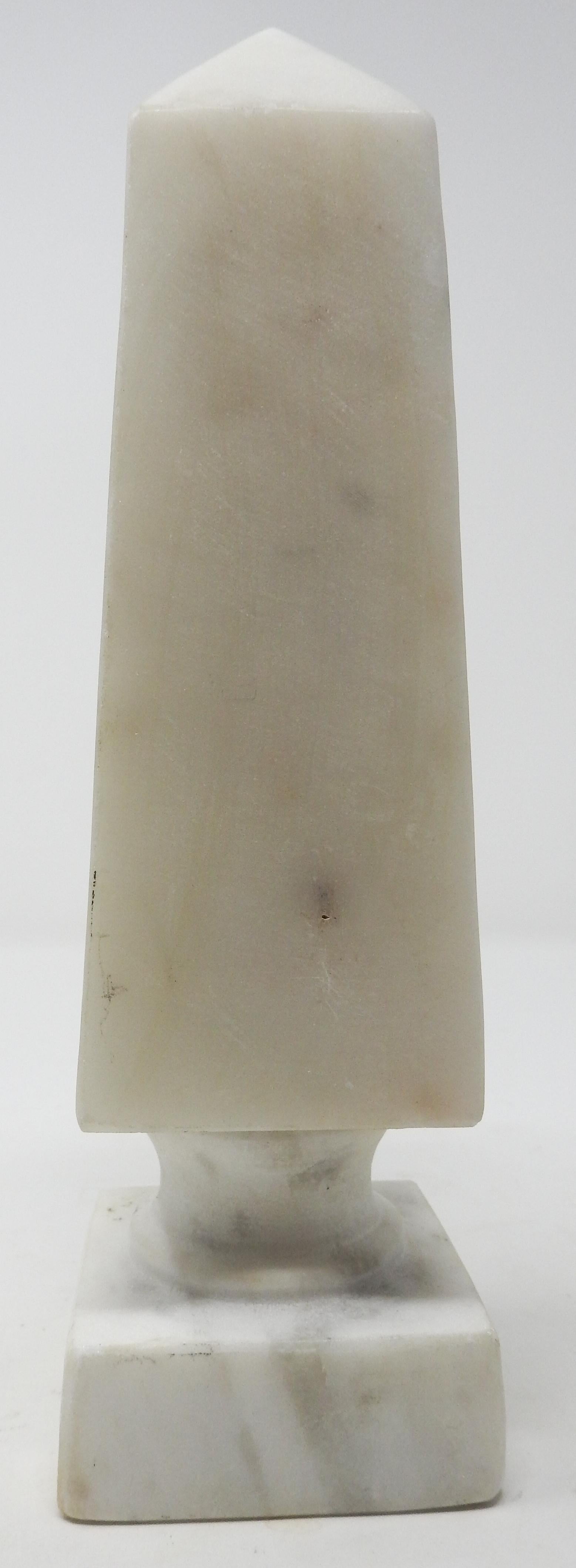 Offering this simple white Carrera marble vintage obelisk. Starting on a square base it rises to a smaller round riser. The main part of the obelisk is scaled evenly with the bottom and makes for a great line to the top.