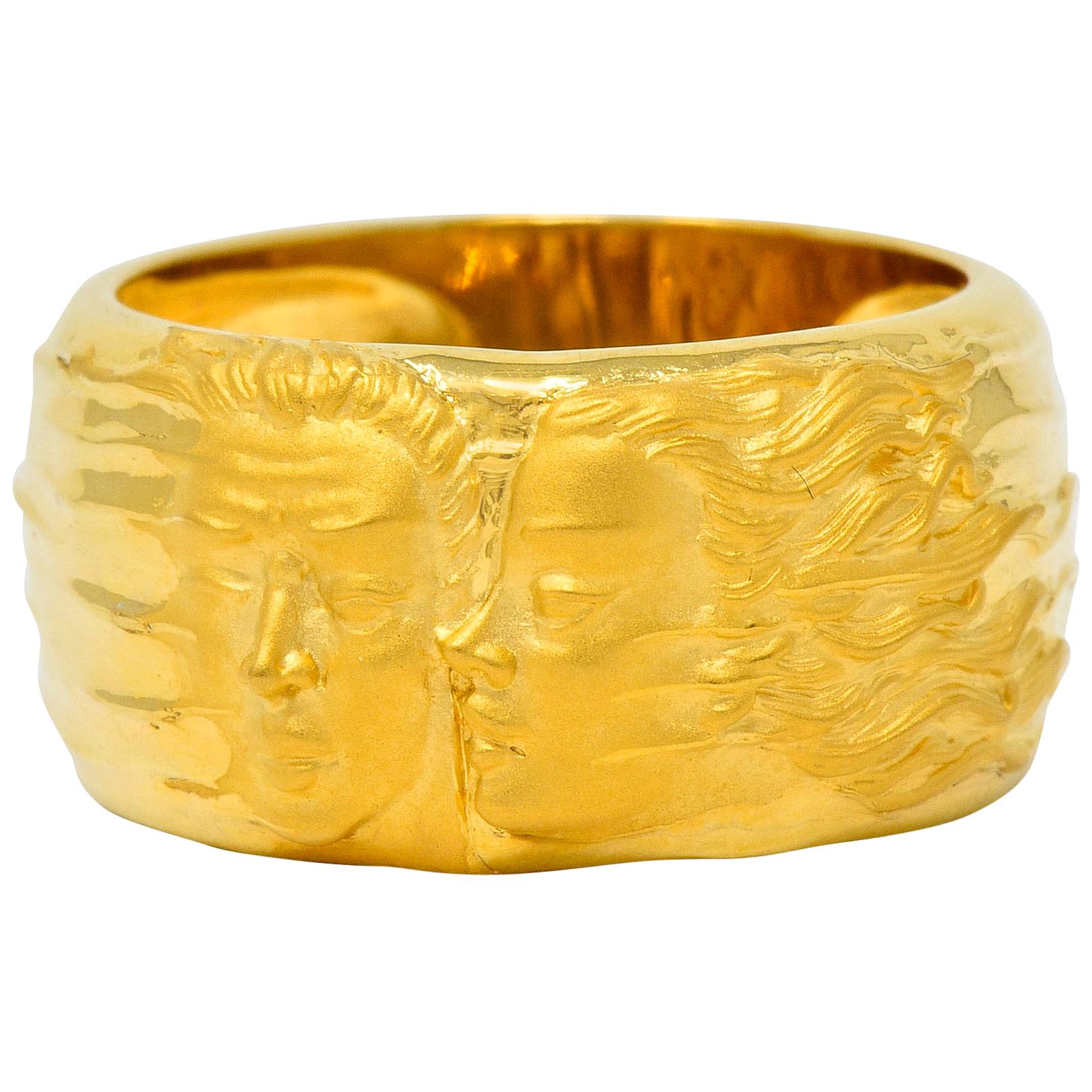 Wide band ring depicting the highly rendered image of Adam's face being kissed on the cheek by Eve's profile

Figures feature a matte gold finish that transitions into a bright windswept polish, accentuated by a waved texture

Numbered with maker's