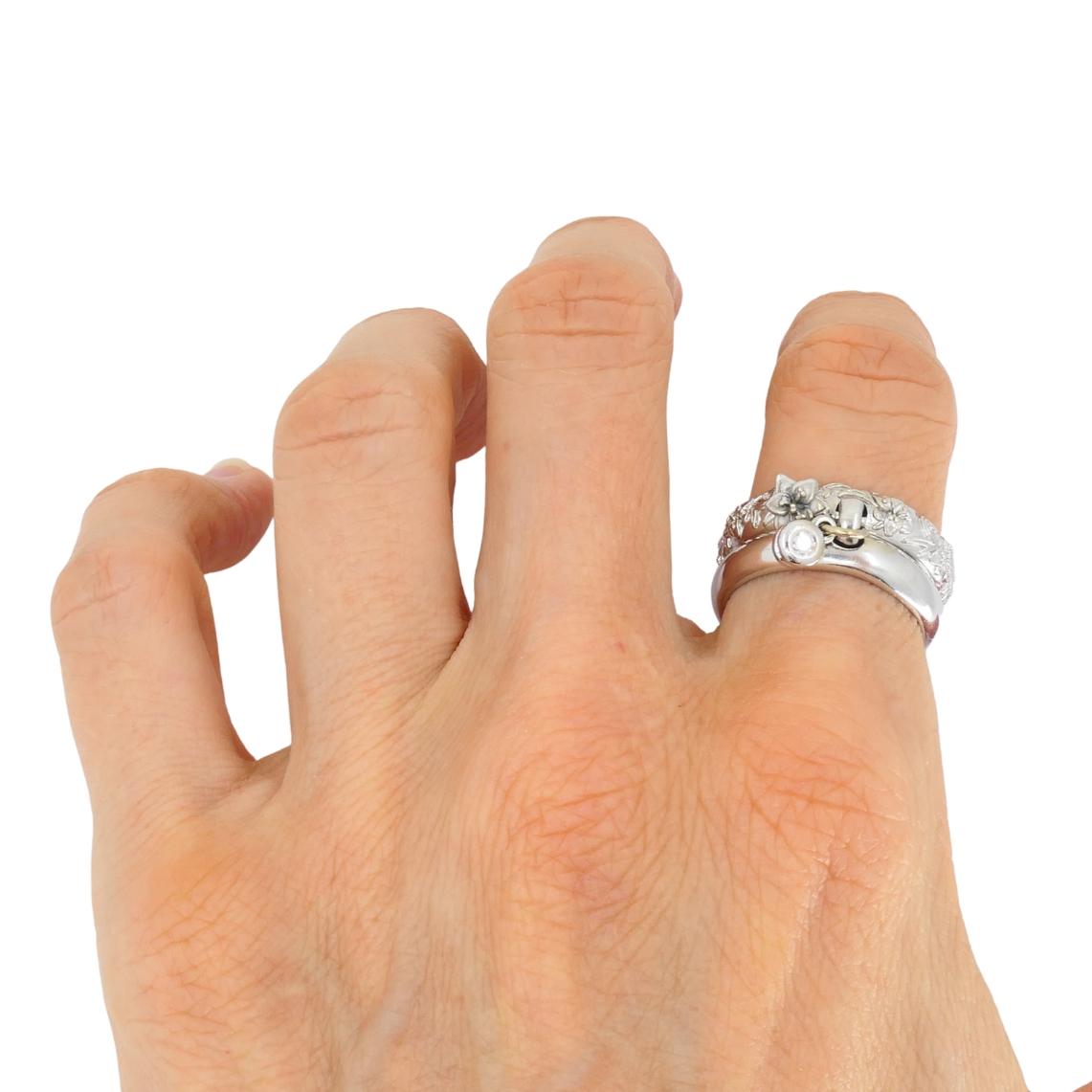 Cette bague vintage Carrera y Carrera est fabriquée en or blanc 18 carats et présente un design distinctif à double bande. L'une des bandes est lisse et polie, tandis que l'autre présente un motif floral détaillé avec des feuilles sculptées et de