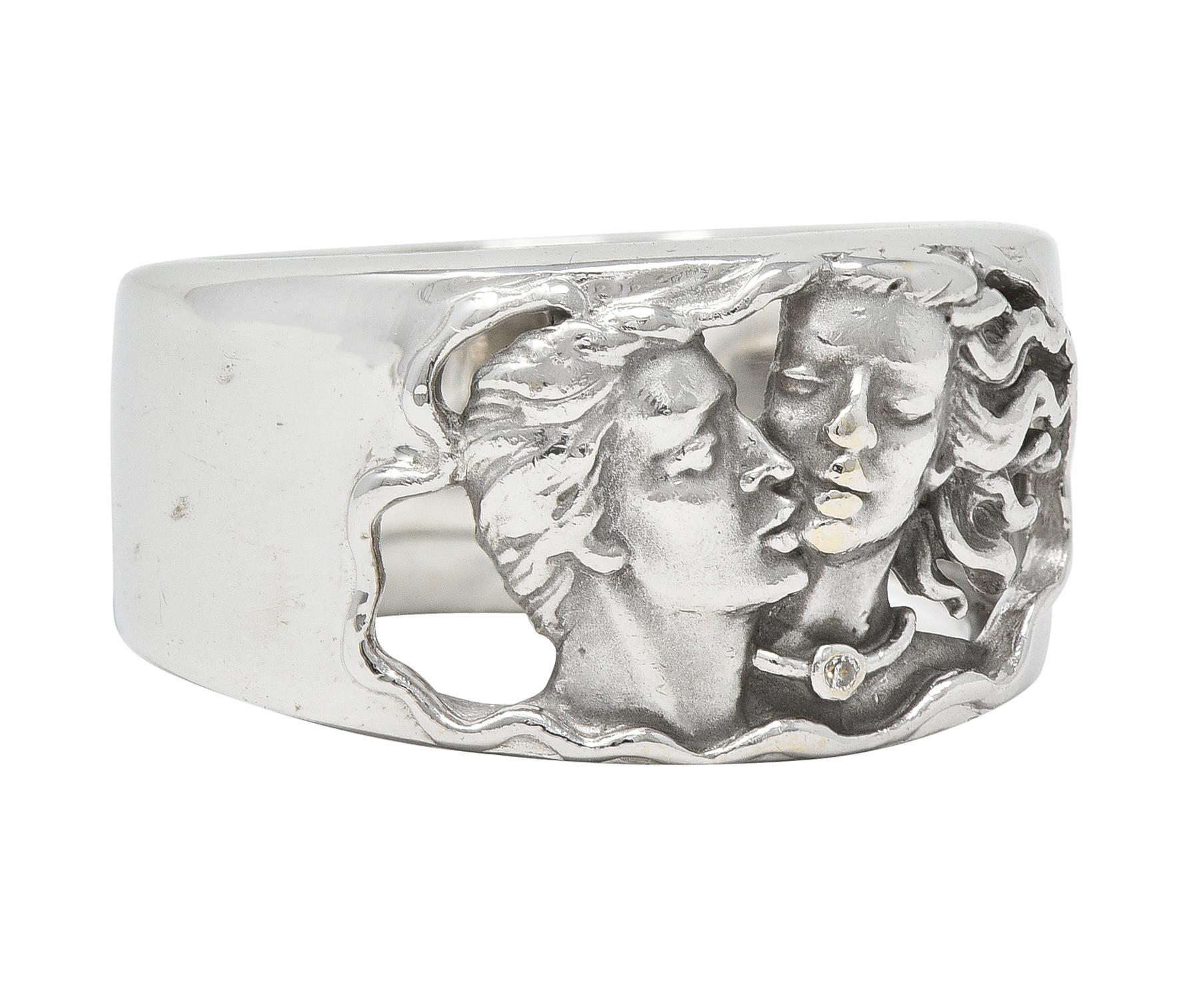 Wide band ring is pierced to front with a depiction of Adam affectionately kissing Eve
Highly rendered with a round brilliant cut diamond accent
Tested as 18 karat gold
Numbered with maker's mark
From the contemporary Adam & Eve collection
Ring
