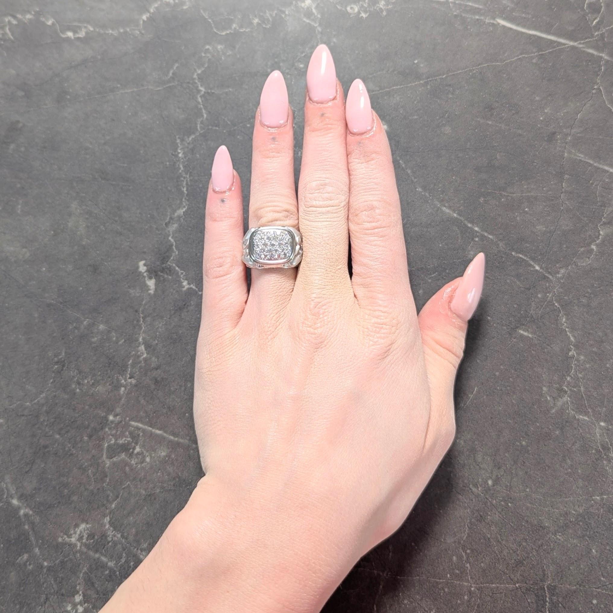 Centra una cara en forma de cojín con pavé de diamantes redondos talla brillante
Peso total aproximado de 0,72 quilates - Color G con claridad VS2
Con un marco estriado de alto brillo y una galería perforada
Flanqueado por hombros con motivos de