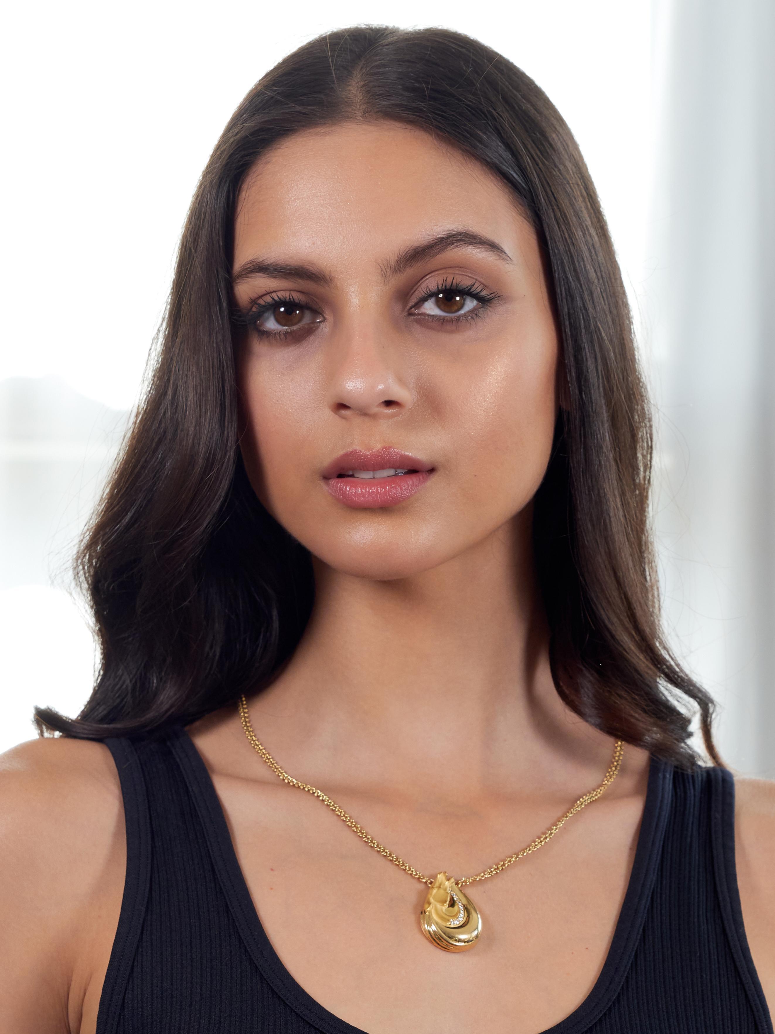 Comprised of stylized curb link chain with know motif links and a central station
Tear-drop shaped and depicting a horse head with sweeping mane
With a grooved matte finish face and high polish hair
Accented by a row of bed set round brilliant cut