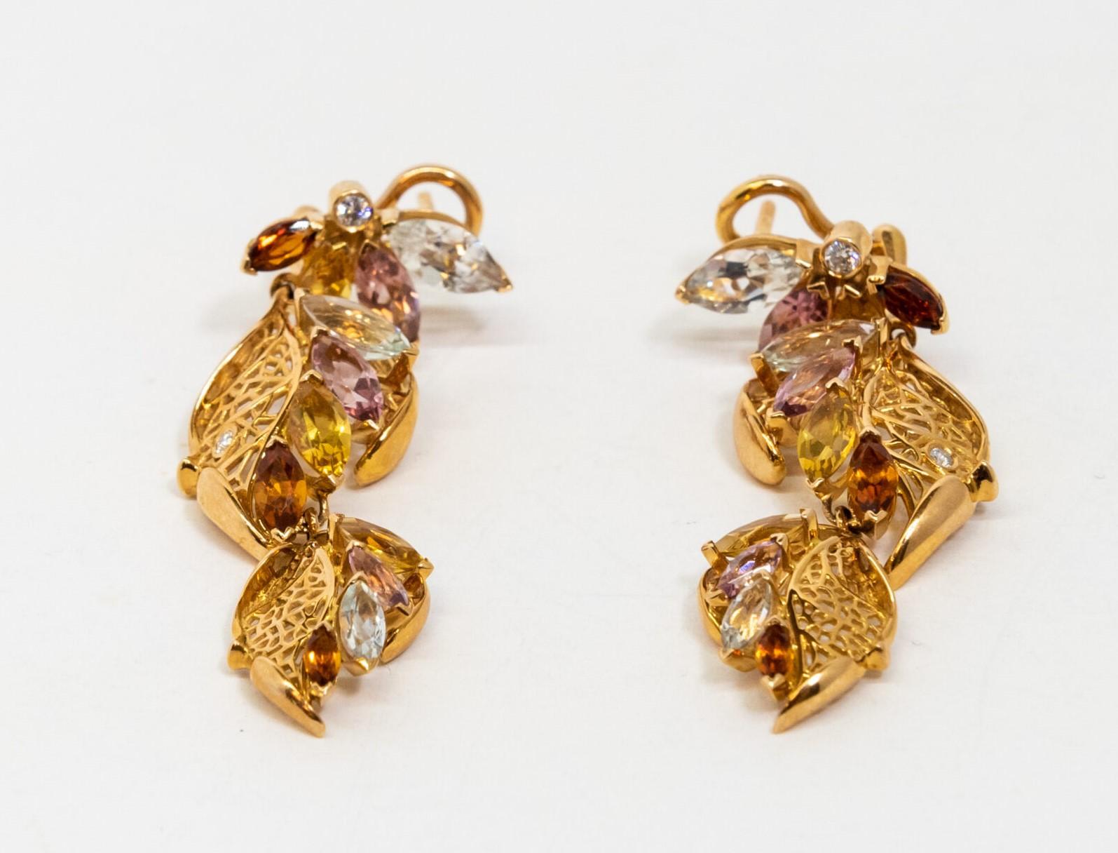 Cette boucle d'oreille pendante en or jaune 18 carats. Figures en forme de feuilles en or jaune 18 carats serties de saphirs bleus, roses, jaunes et orange et de diamants. Dos français.

Dimensions : 5,2 cm x 1,7 cm