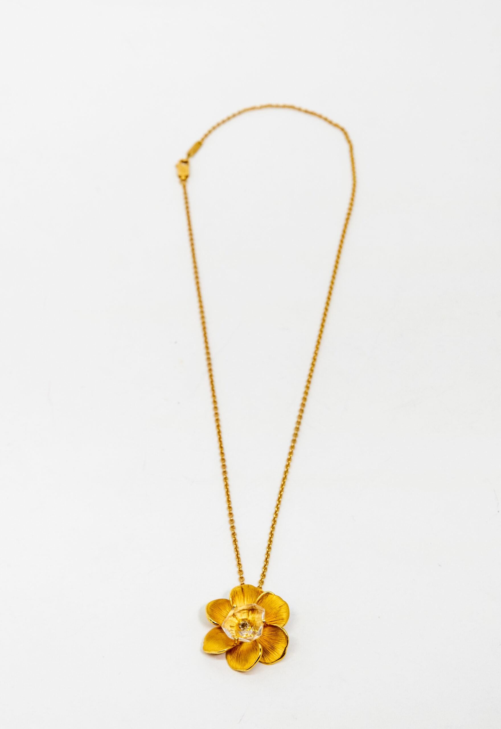 18K Yellow Gold pendant. 18K Yellow Gold Rolo chain with lobster claw lock. The floral yellow gold pendant is decorated with diamond (~0.07ct) which is covered by crystal rock (~1.00un)

Length: 24 cm