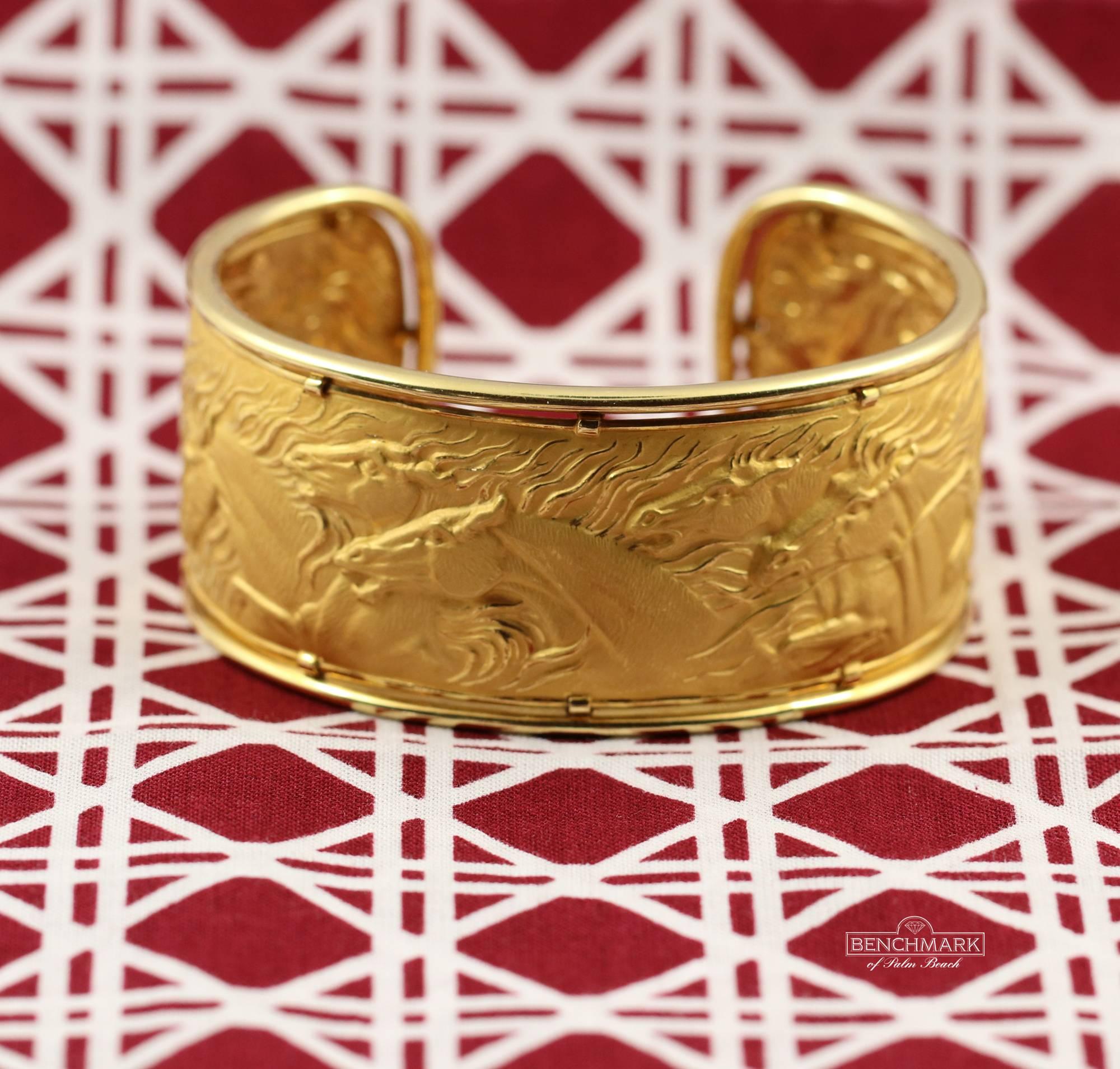 An 18 karat yellow gold bracelet framed in high polish gold, with seven galloping horses in the center. Masterfully textured and with great relief, the horses appear to gallop. Measuring 1 1/8 inches wide it will comfortably fit wrists up to 6 1/2