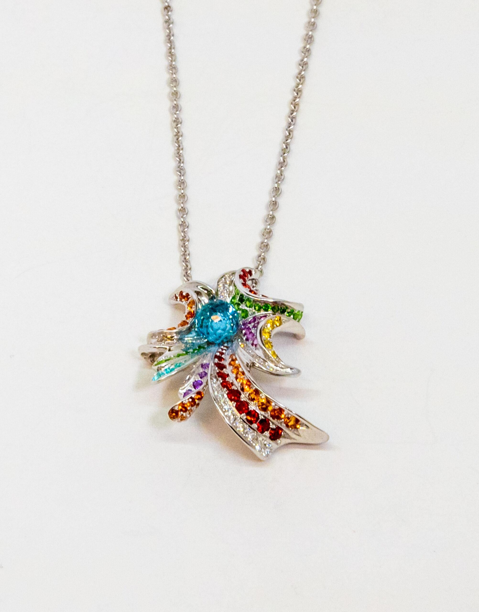 18K White Gold pendant. 18K White Gold cable chain with lobster claw lock. The pendant is set with light blue, purple, red, yellow, orange, pink, green sapphires and diamonds (~0.34ct). Dancing blue Tourmaline in the middle (8.00 un)

Chain Length: