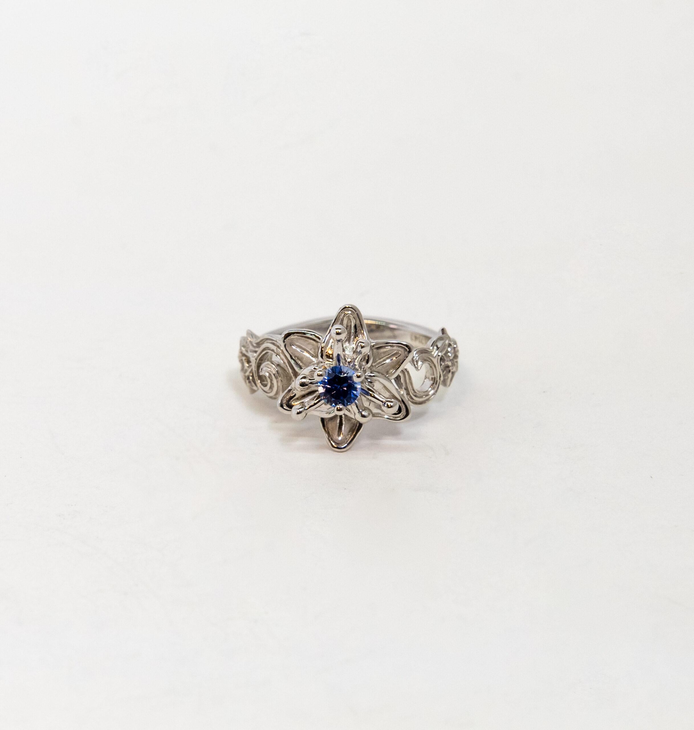 This ring is made of 18K White Gold. It is decorated as floral pattern with a round-cut blue Sapphire (~0.25ct).

Size – 54.5 (7 US)