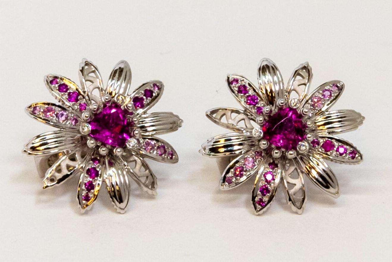 18K White Gold stud earring. It is designed as flower-shape with a round-cut Tourmaline in the middle and 3 diamonds around (totaling ~0.02ct). Five “petals” set with 4 pink Sapphires each (totaling ~0.38ct) . French back.

Dimensions: 2.1 cm x 2.1