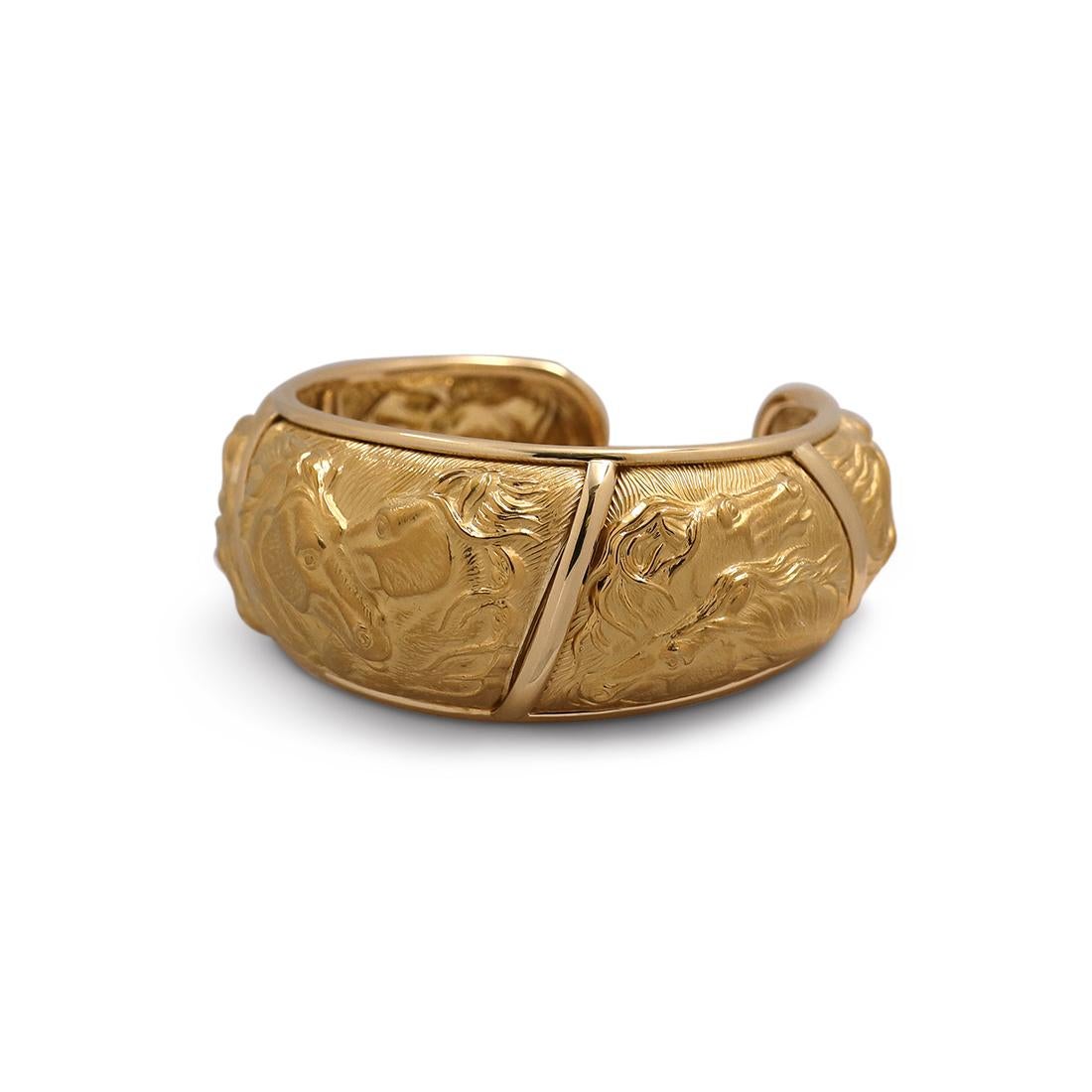 Authentic Carrera y Carrera 'Mosaico' cuff crafted in 18 karat yellow gold. The cuff is crafted using the repoussé technique featuring two horses in five separate scenes. The cuff measures 27mm in width at its widest and 20mm at its narrowest. The