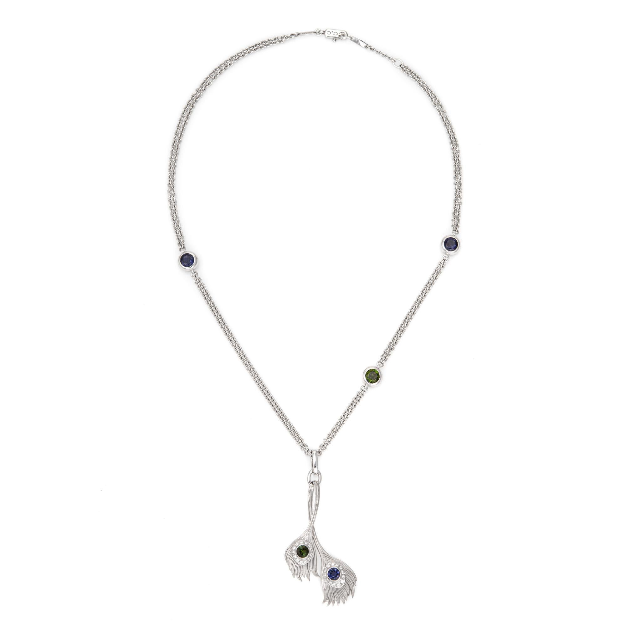 Stylish pre-owned Carrera y Carrera peacock necklace crafted in 18 karat white gold.  

The pendant and chain are set with 4mm iolite and tsavorite garnets. Diamonds total an estimated 0.15 carats (estimated at H-I color and VS2-SI1 clarity). The