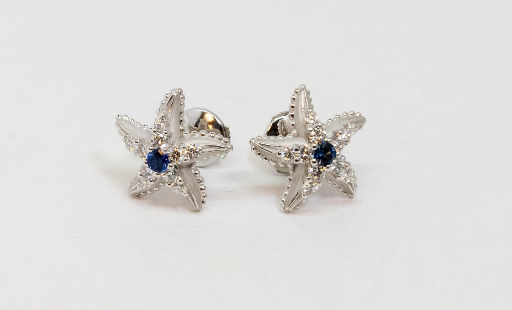 18K White Gold stud earring. It is star-shaped earrings set Blue Sapphire main stone (~0.22ct) and 10 Diamonds around (~0.57ct). Push back.

Dimensions: 1.7 cm x 1.7 cm