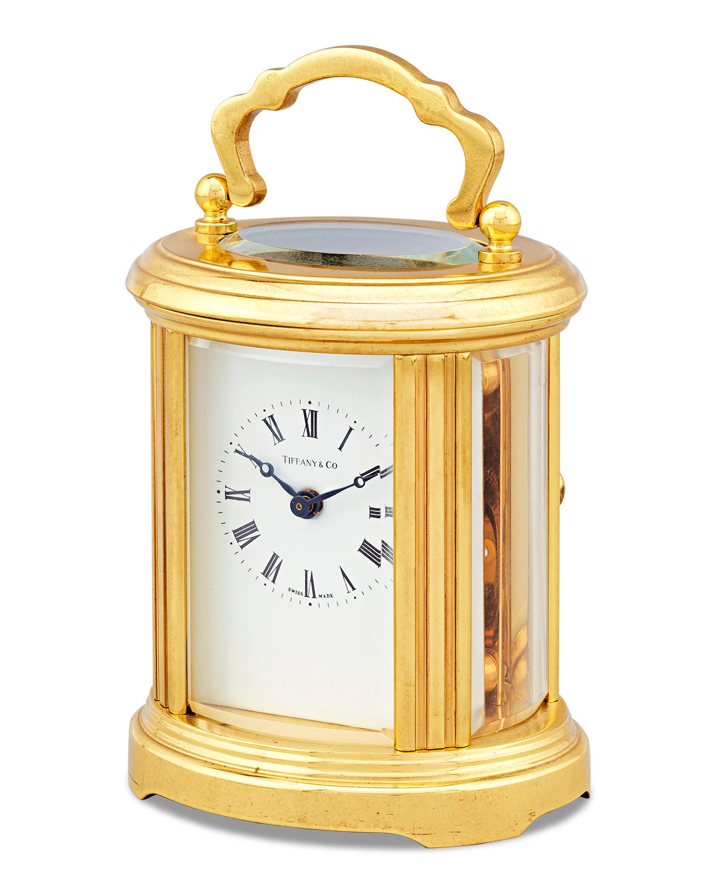 This brass carriage clock epitomizes the timeless luxury of Tiffany & Co. The impressive timepiece is housed in a solid brass frame, complete with a hinged handle for ease of travel. It tells the time on a classic Roman numeral face, while a Swiss