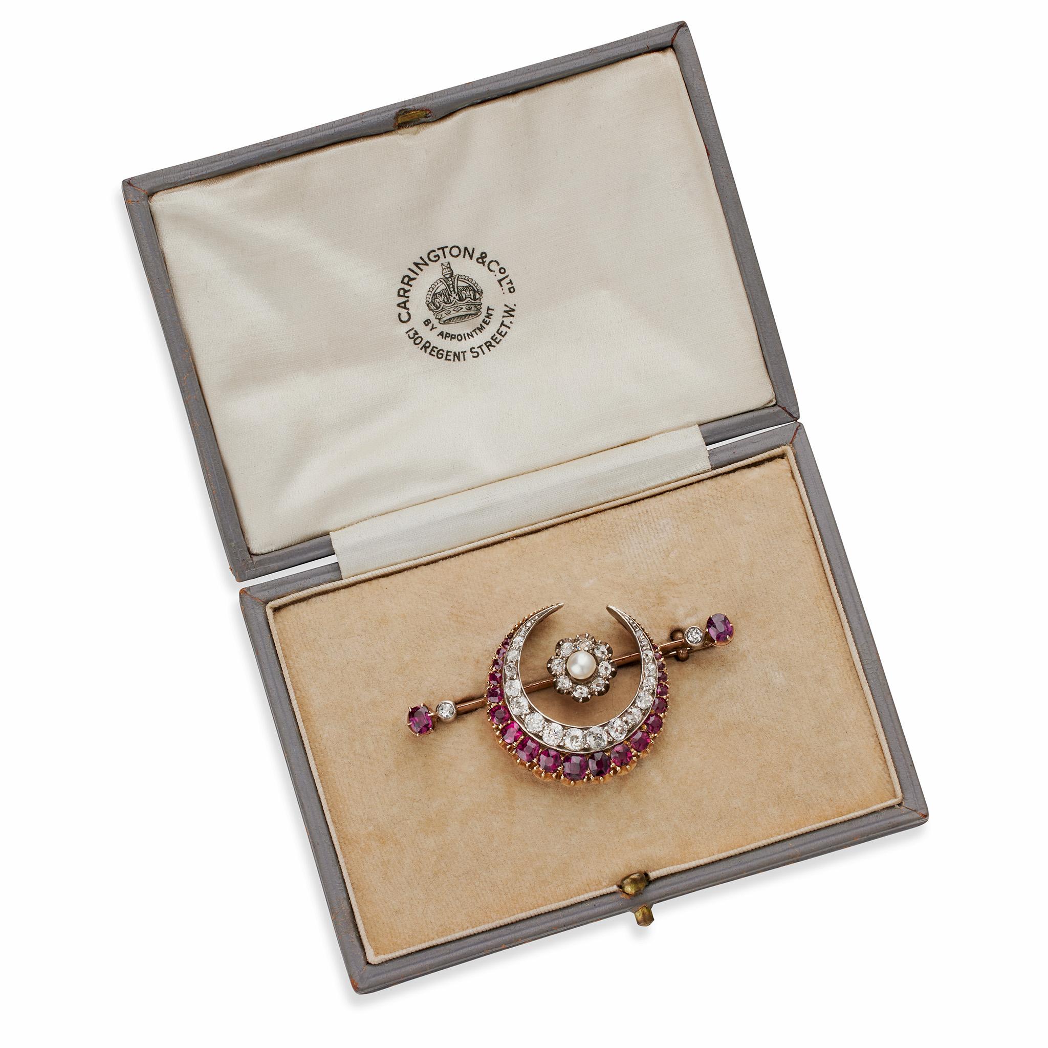 Created in the 1890s by Carrington & Co., Regent Street, London, this English crescent moon brooch is composed of rubies, diamonds and a pearl. The brooch is designed as a tapering circular crescent moon of graduating old mine-cut diamonds edged by