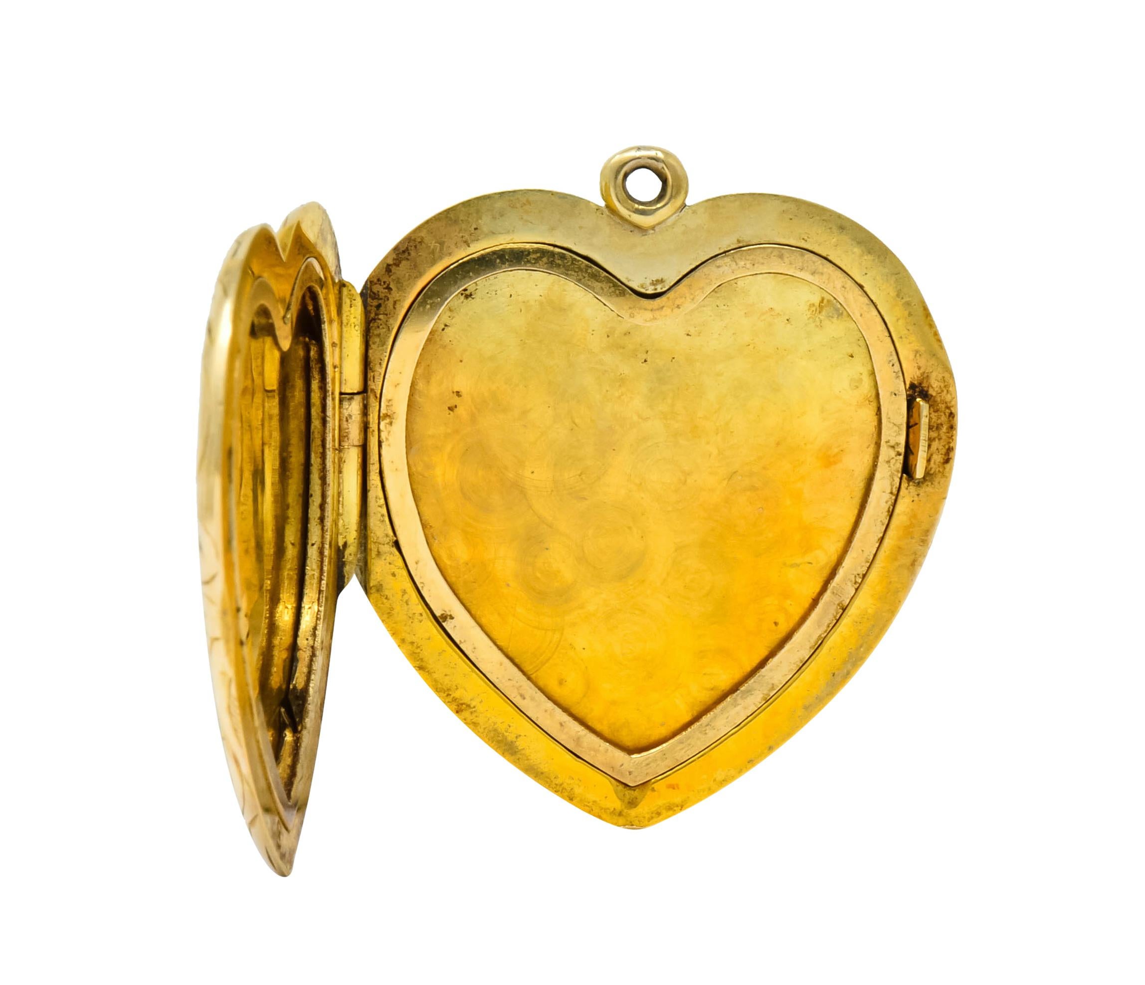 Locket designed as heart deeply engraved on front with scrolling foliate motif centering a stylized flower

Hinge opens to reveal two recessed areas with removable heart frames to hold keepsake in place

With maker's mark for Carrington Co. and