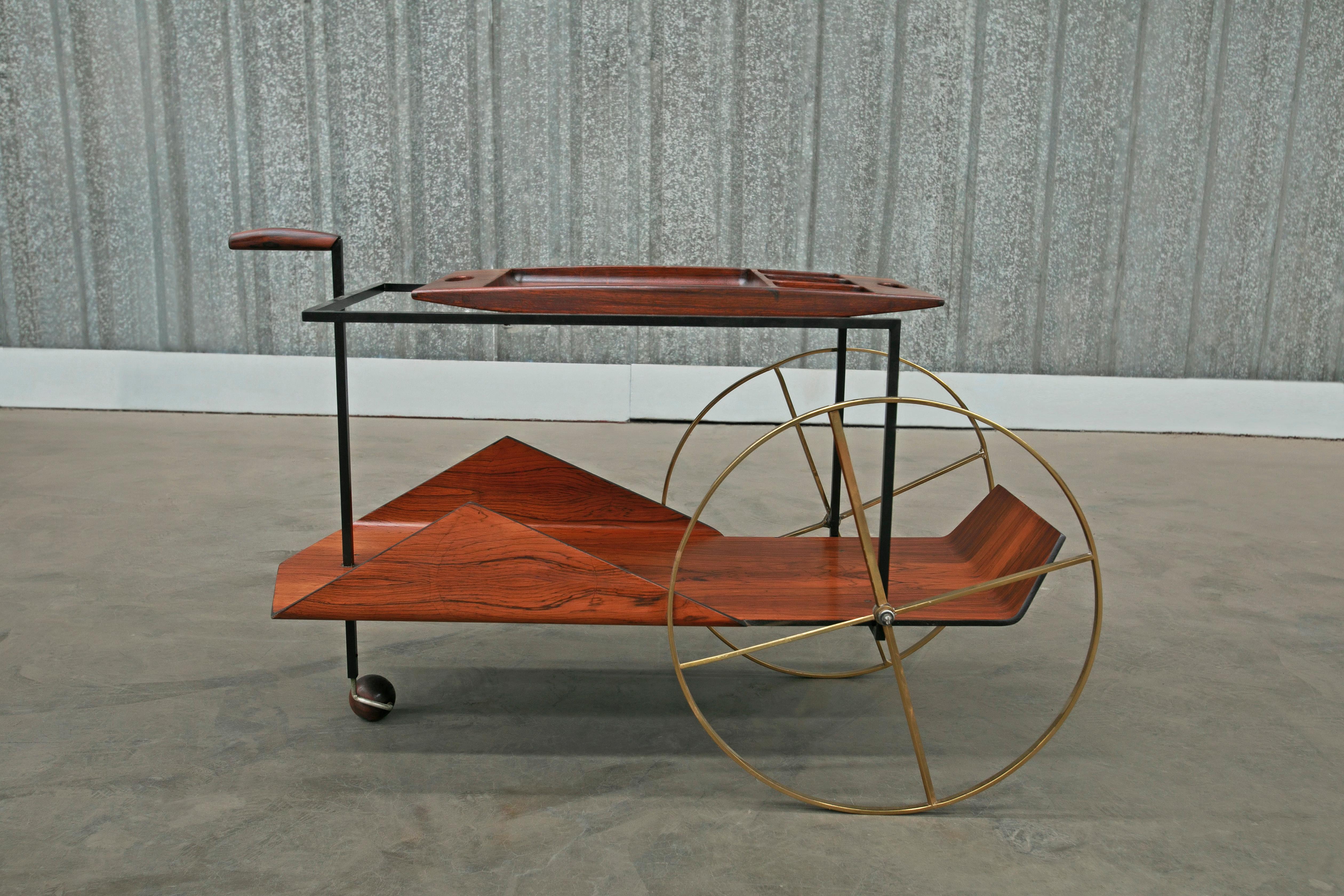 Jorge Zalszupin’s iconic “Carrinho de Cha” bar cart is made with Brazilian rosewood (also known as jacaranda) and features an iron frame and brass wheels. The wood has been expertly refinished and the iron and brass has been repolished to ensure