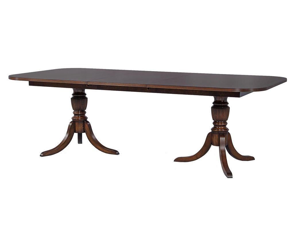 Classic flamed mahogany English Duncan Phyfe style dining table finished in house by Carrocel craftsmen in our custom Imperial Ember satin finish with a contrasting enriched satinwood banding. Table includes two extension leaves measuring W 22”