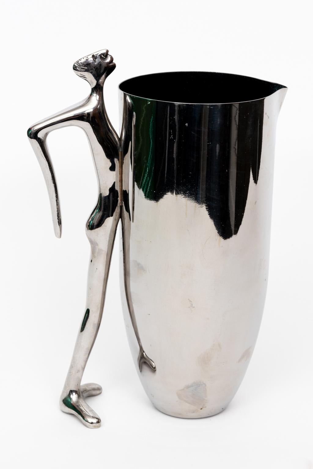 Circa 1980s stainless steel and aluminum water jug or vase by South African artist and designer Carrol Boyes. The sculptural handle depicts a man leaning into the pitcher. Made in South Africa. Please note of wear consistent with age. The piece