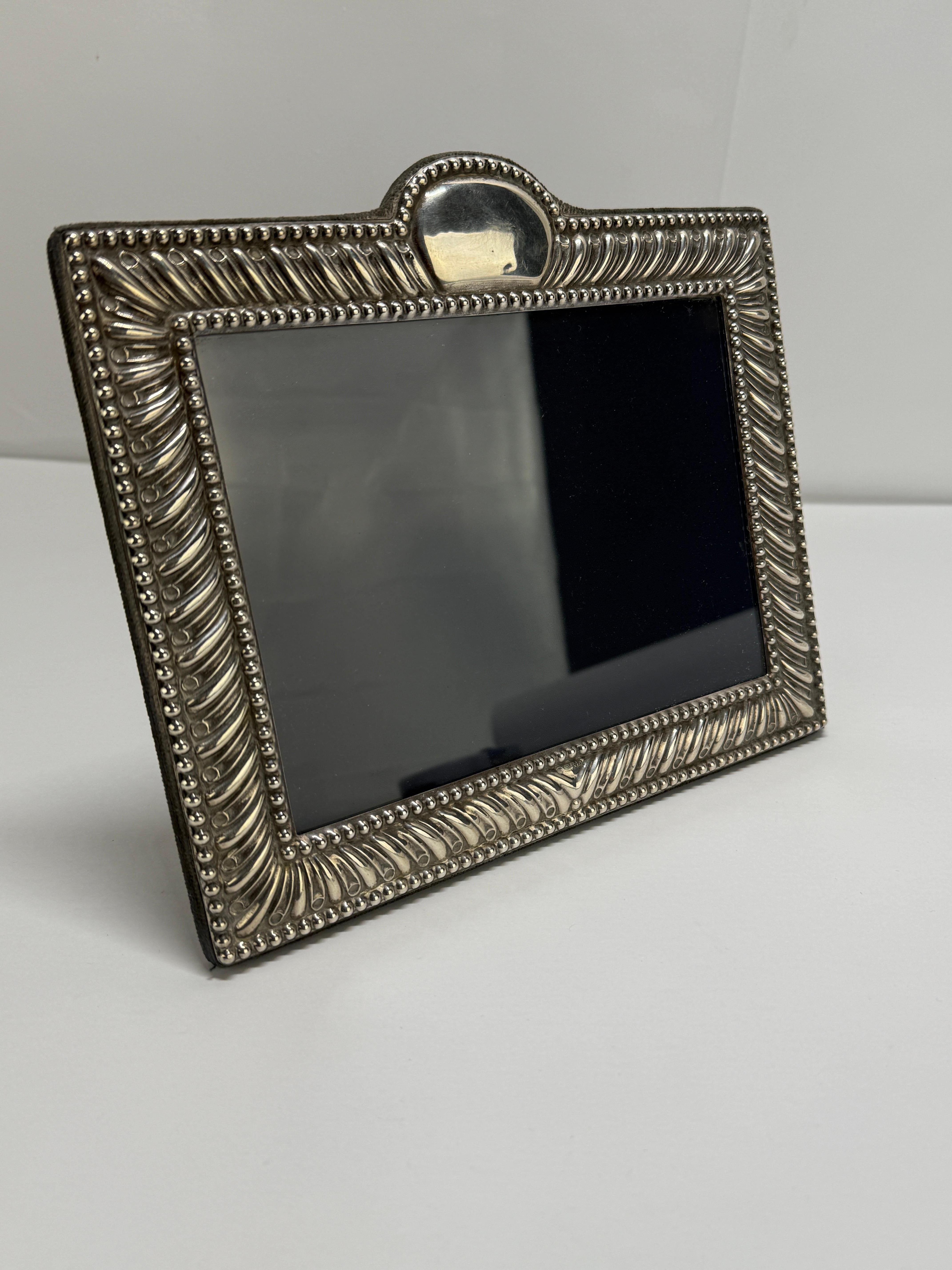 A British sterling silver photograph frame, fully hallmarked for London, 1990, with maker’s mark for Carrs of Sheffield. The rectangular surround is worked in alternating diagonally fluted panels and raised beading, a design that borrows from late