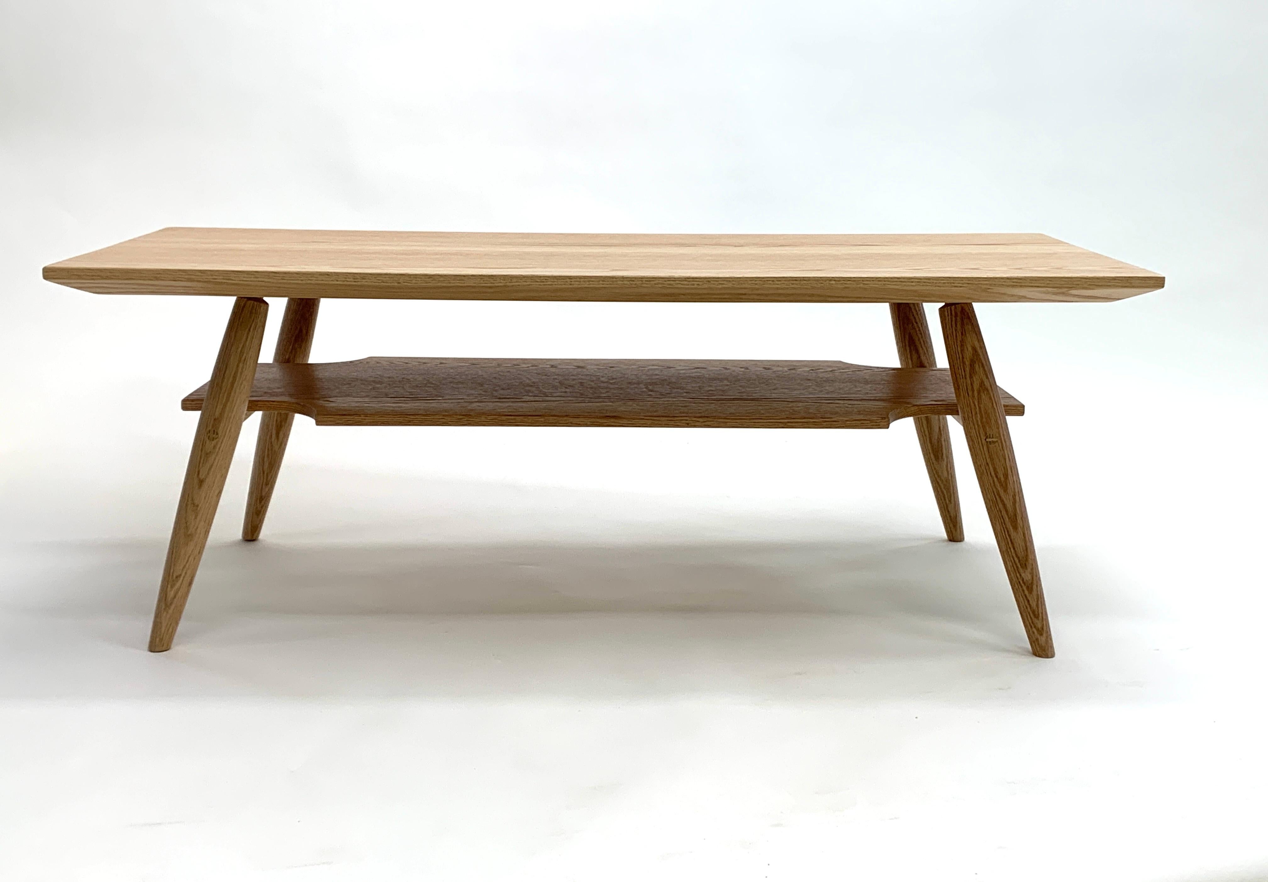 La table basse Carry Underwood est une table basse élégante, inspirée du milieu du siècle dernier, avec un espace de rangement en dessous.  Véritable menuiserie traditionnelle, avec des cales sur les tenons des rails pour garantir une durée de vie