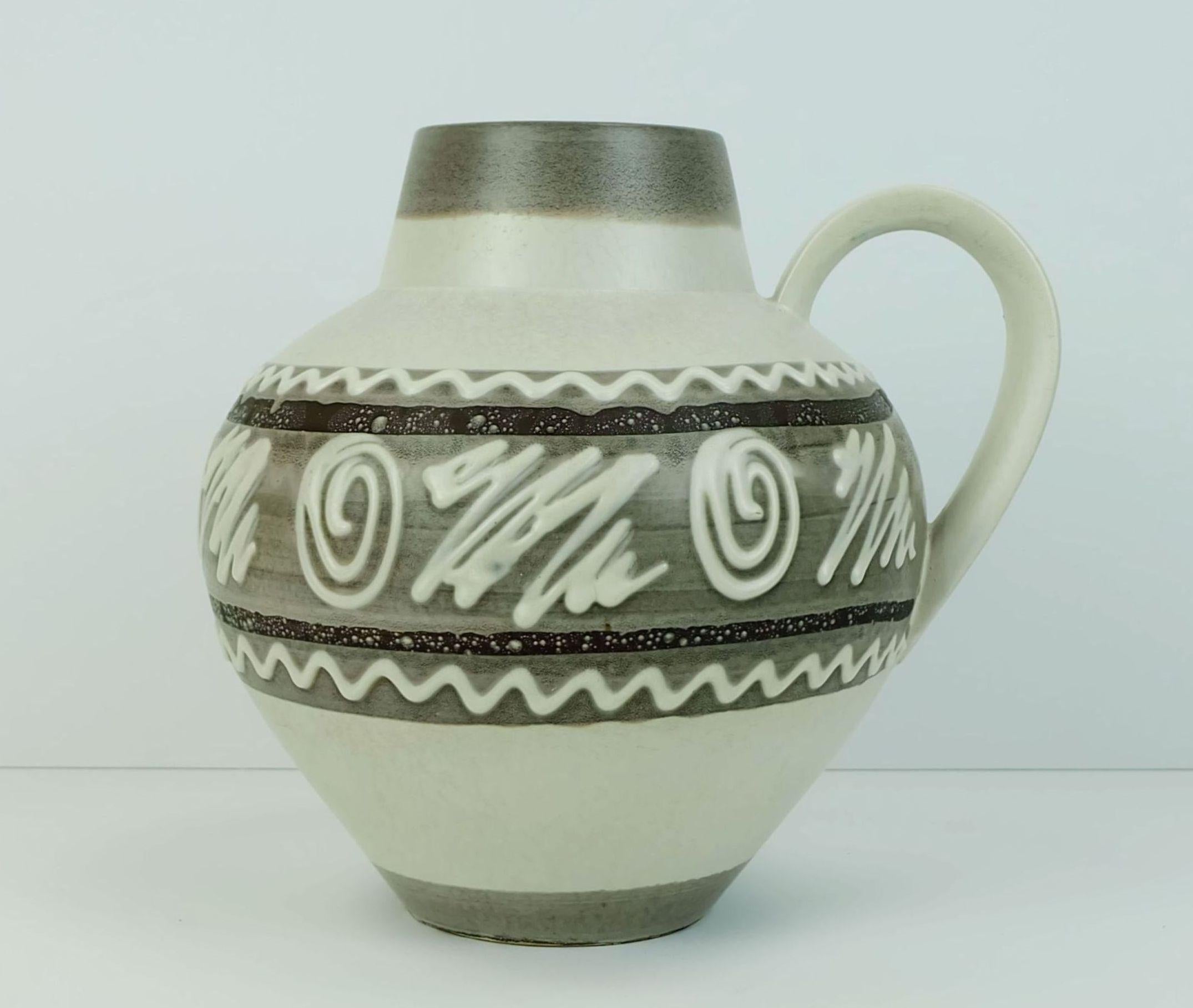 Un fantastico vaso vintage della Germania occidentale prodotto da Carstens-Keramik tra il 1963 e il 1965. Bellissima variazione di smalto in bianco e diverse tonalità di marrone e un motivo astratto. Modello 698-23. 

Altezza 9 1/2