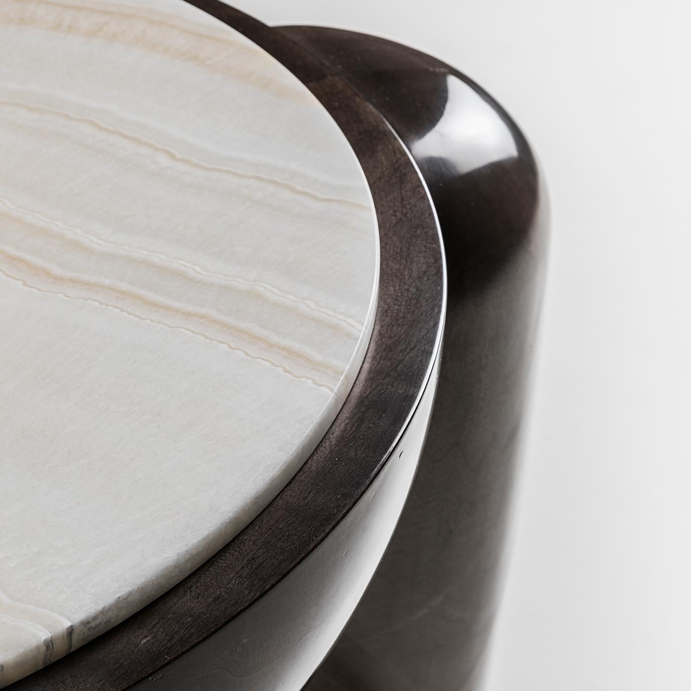 Captivating and bold, this side table combines natural elements in a sculptural form that will bring interest to a modern seating ensemble. Showcased by a footed eucalyptus base with a glossy finish, the top is a superb circle of white marble whose