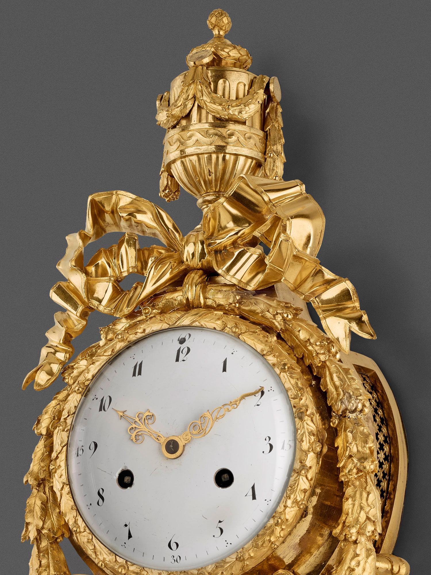 French, European, Cartel Gold Plated Wall Clock with Vase Top, Paris, Late 18th Century, Louis XVI

The case decorated with playful ornaments is cast in bronze, chased, fire-gilded and the surface partly polished. Elaborately bound garlands of